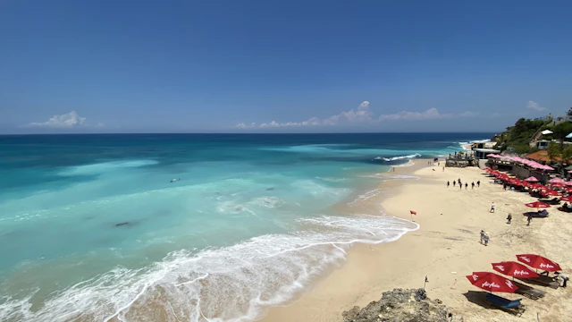 Dreamland Beach's turquoise surf and red umbrellas below the cliff (people far off)
