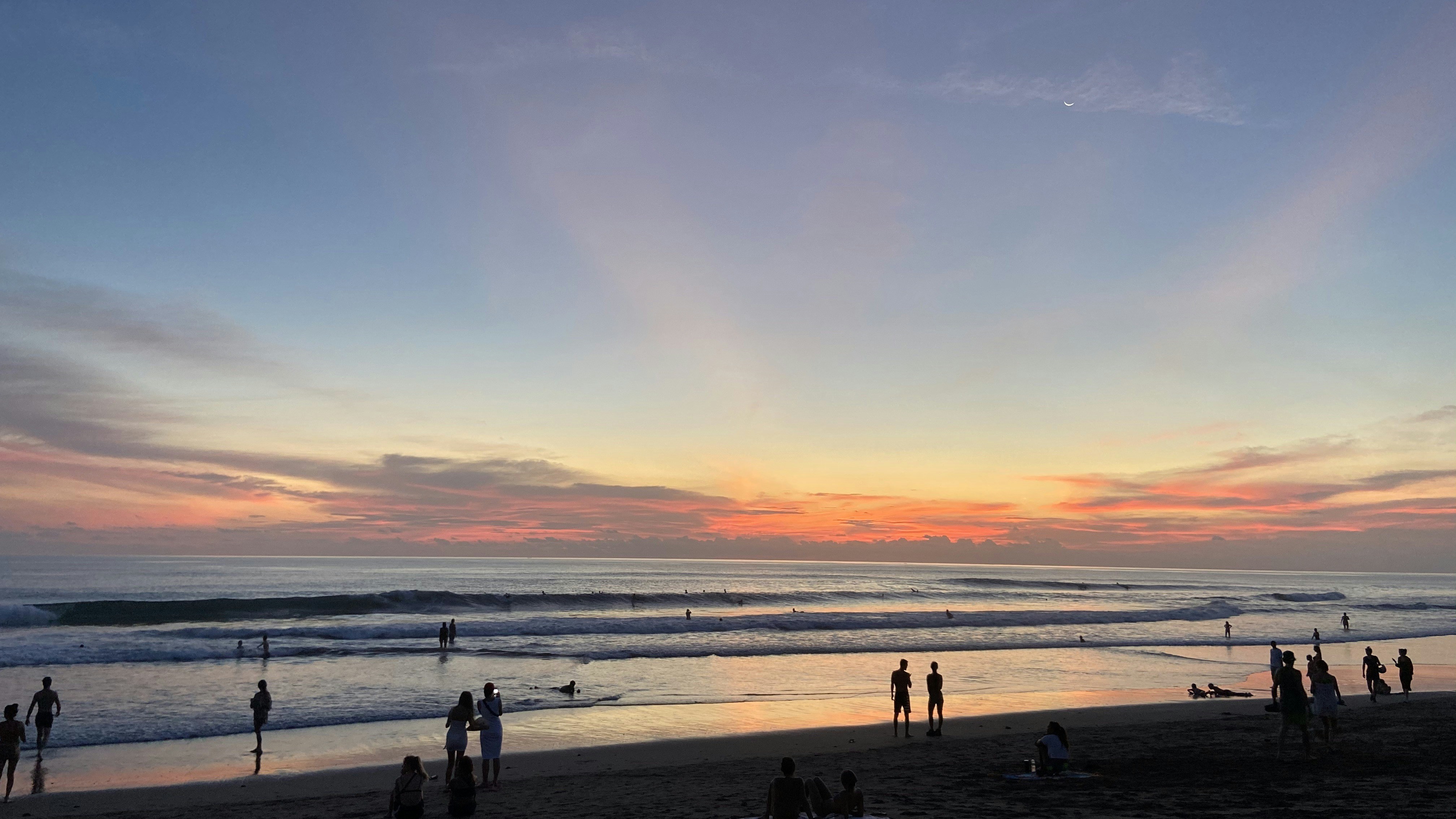 Um grupo de pessoas em pé no topo de uma praia ao lado do oceano