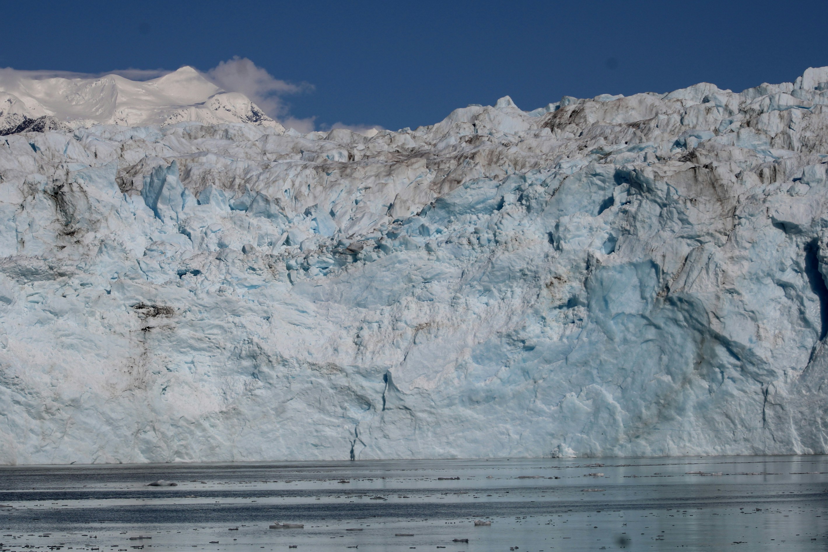 A large iceberg with a boat in front of it