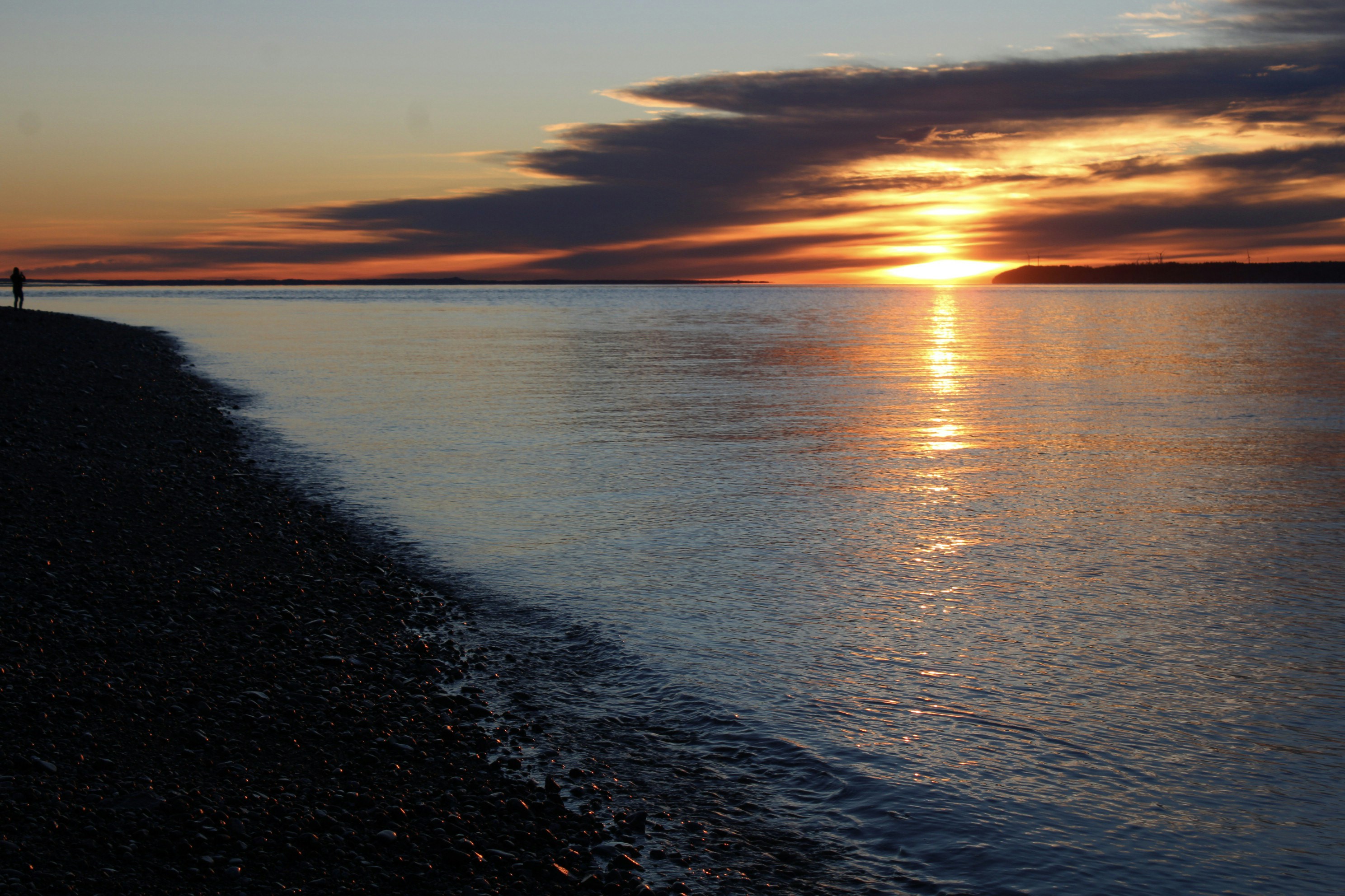 A person standing on a beach at sunset