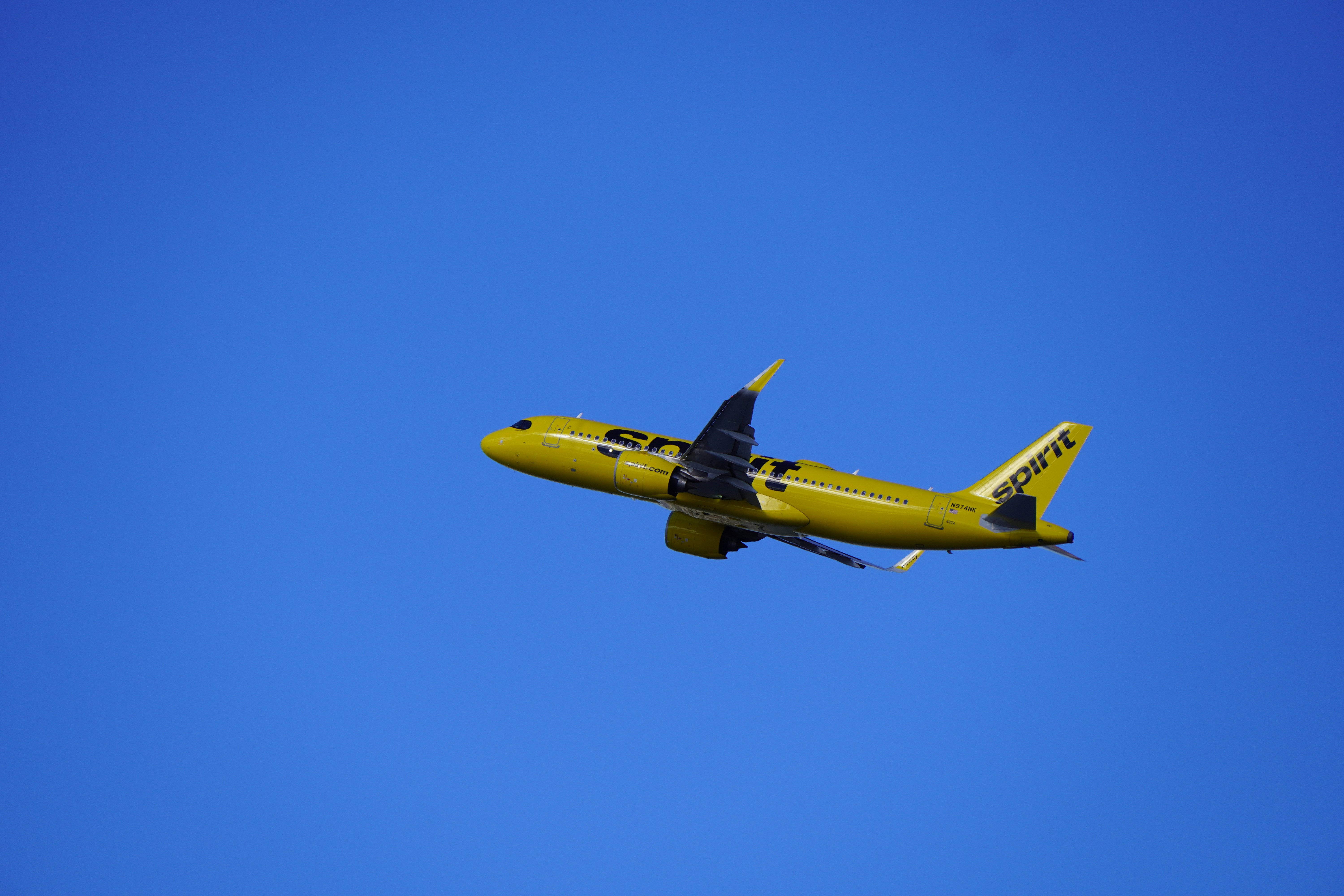 A yellow airplane flying through a blue sky