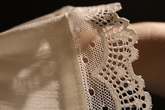 A close up of a person's hand holding a piece of lace