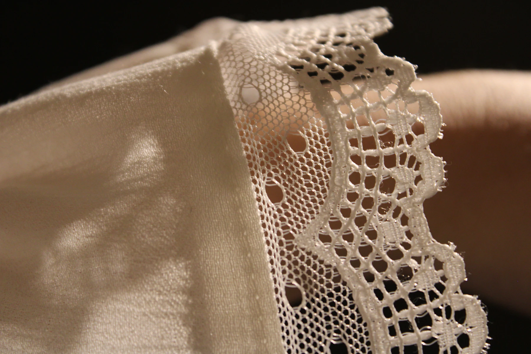 A cotton lace edge on cream cloth in soft light
