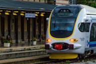 A white and blue train traveling past a train station