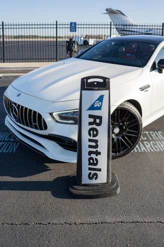 A white car parked next to a parking meter