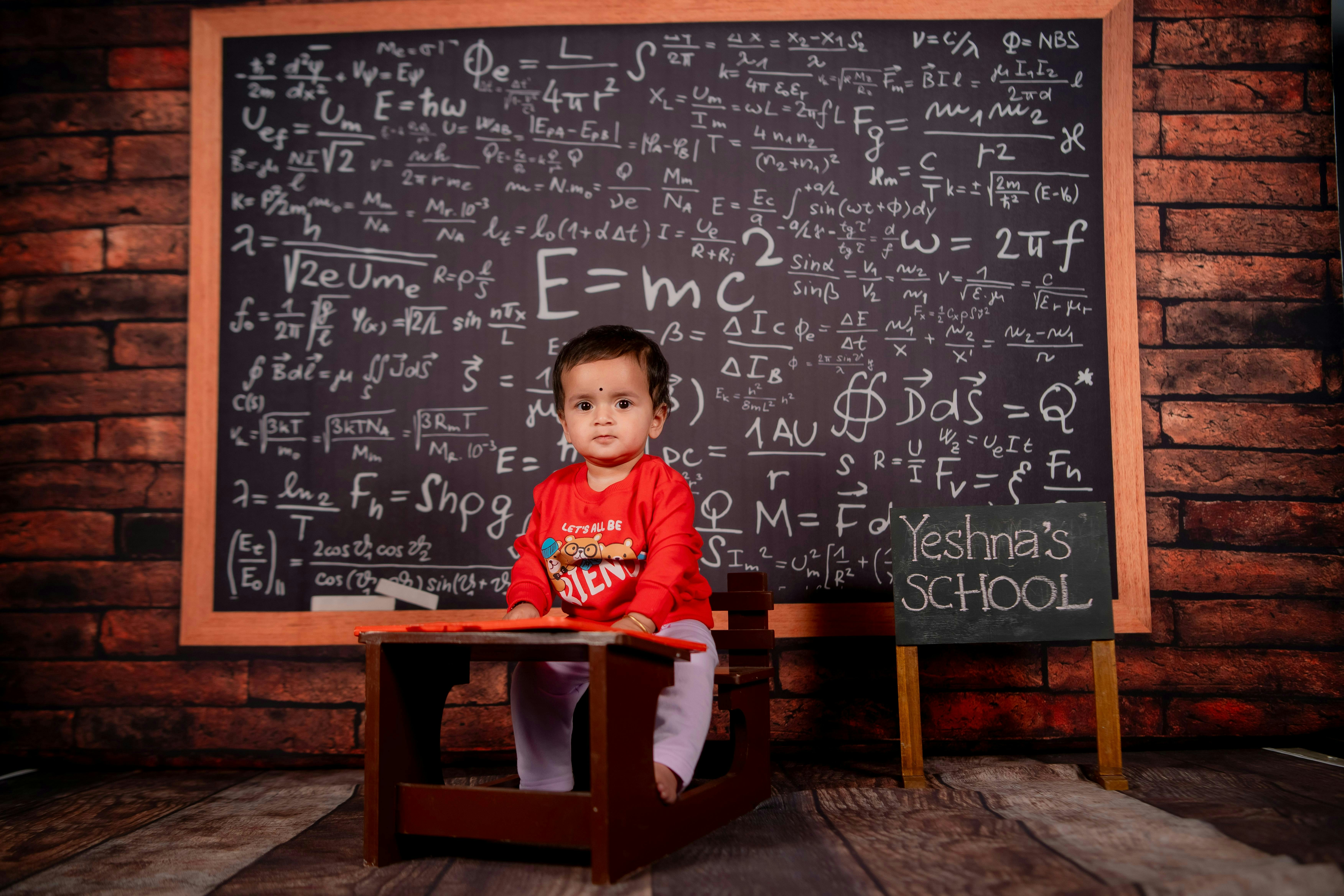 A little boy sitting at a desk in front of a chalkboard