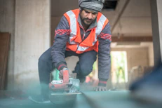 A man in an orange vest is working on a piece of metal
