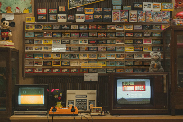 A room with two televisions, a radio, and a wall of movies