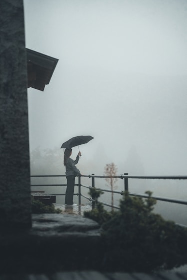 A person holding an umbrella standing on a balcony