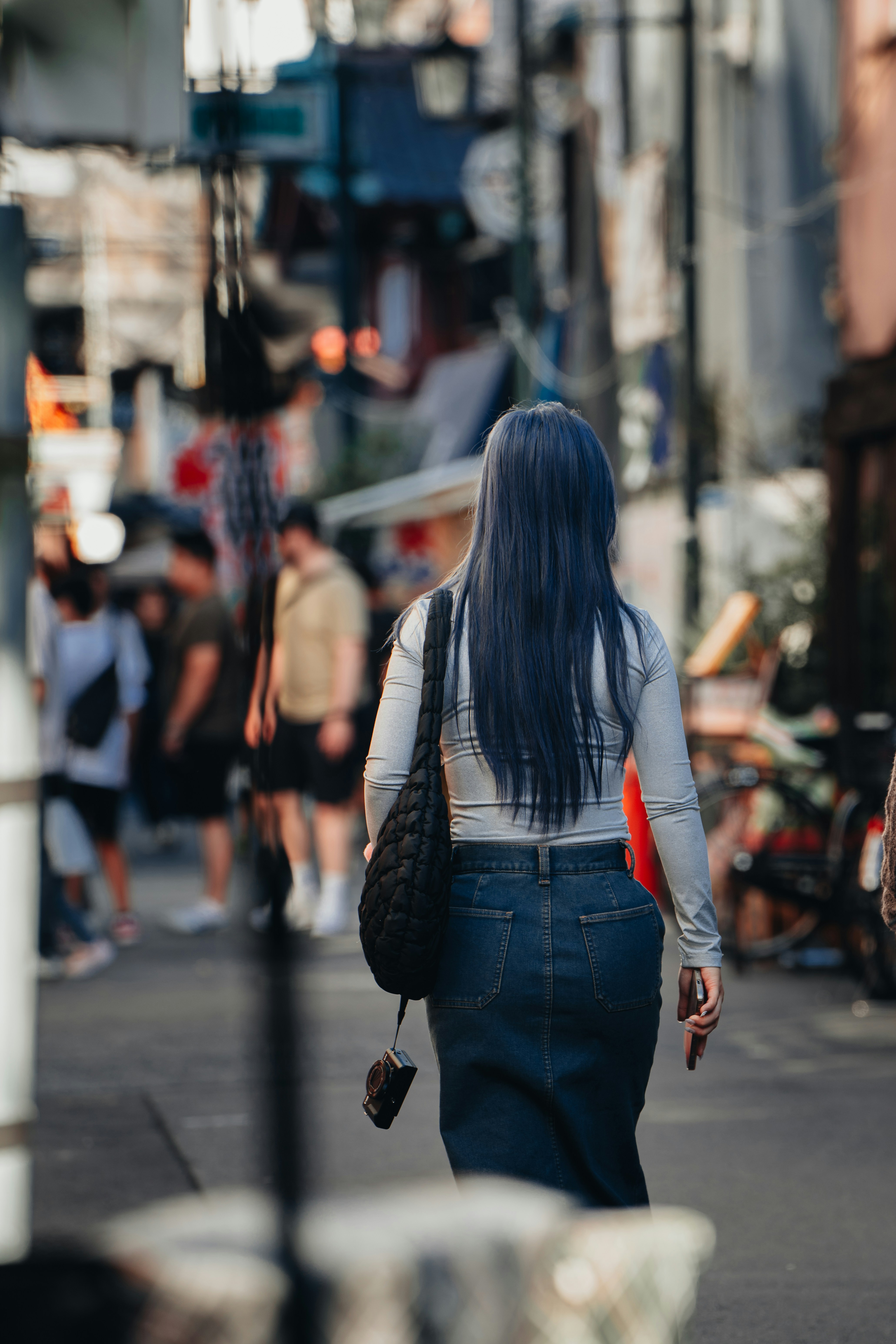 A woman walking down a street next to a tall building
