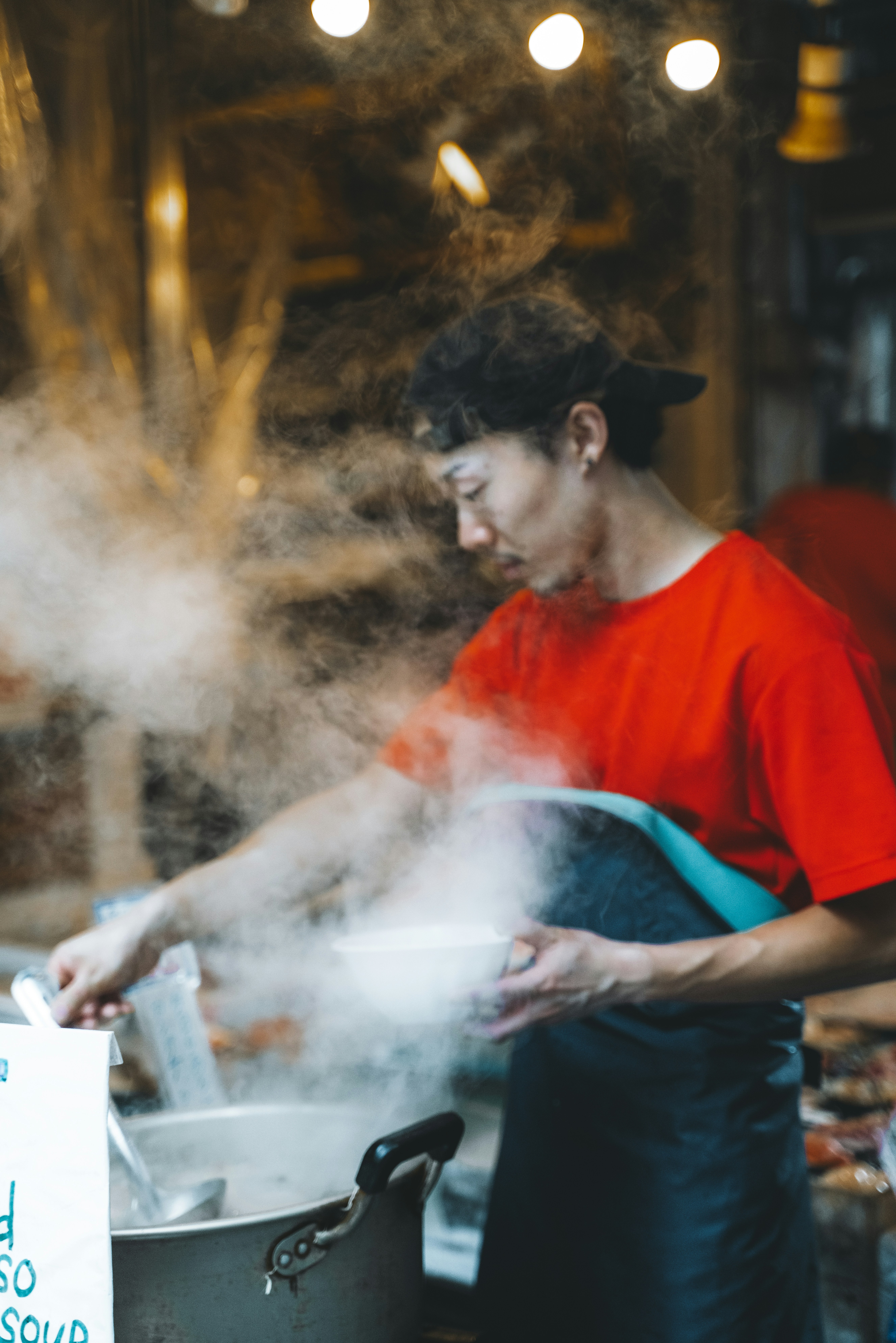 A man cooking food in a pot with steam coming out of it
