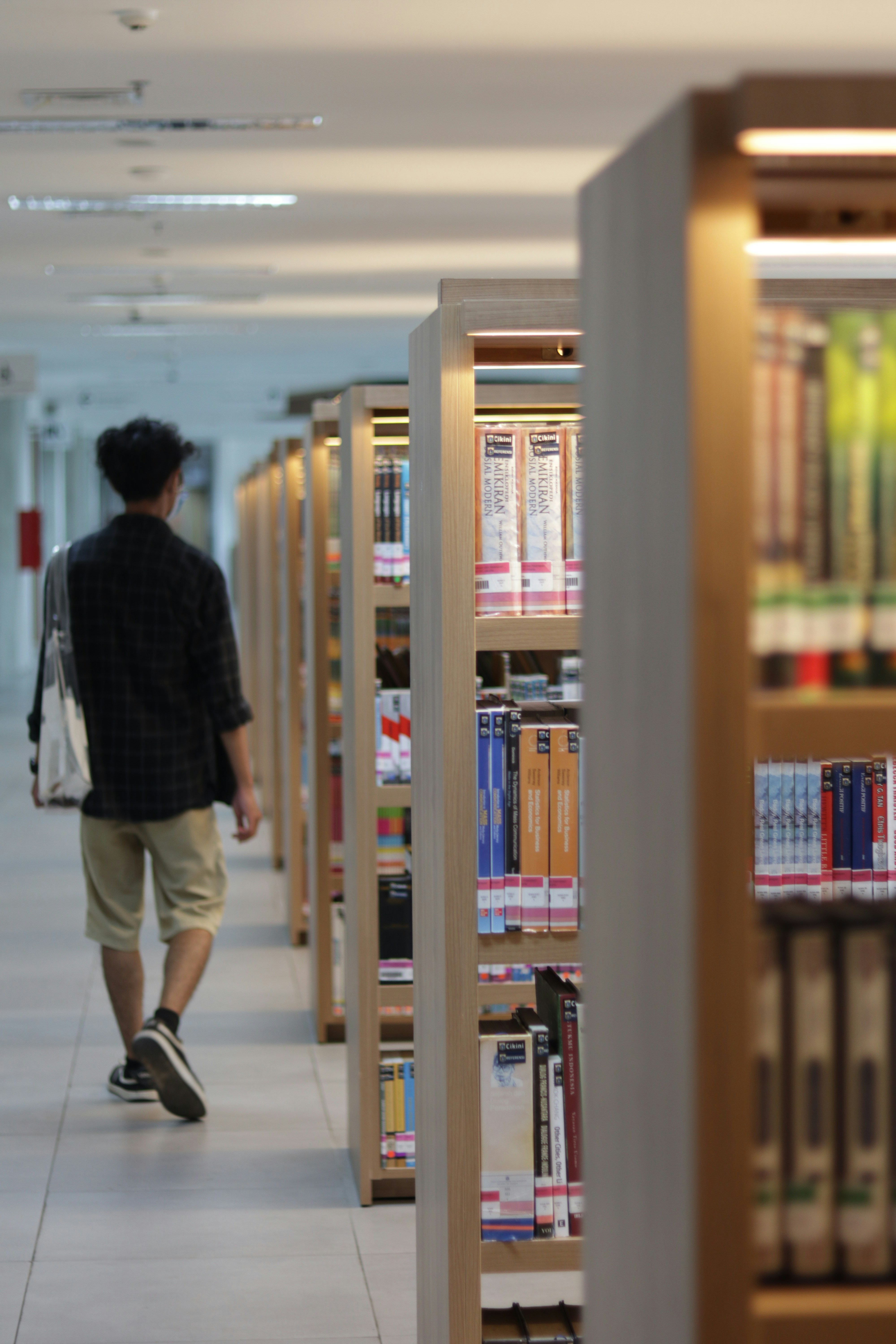 A man walking through a library filled with books