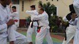 A group of men practicing karate in front of a building