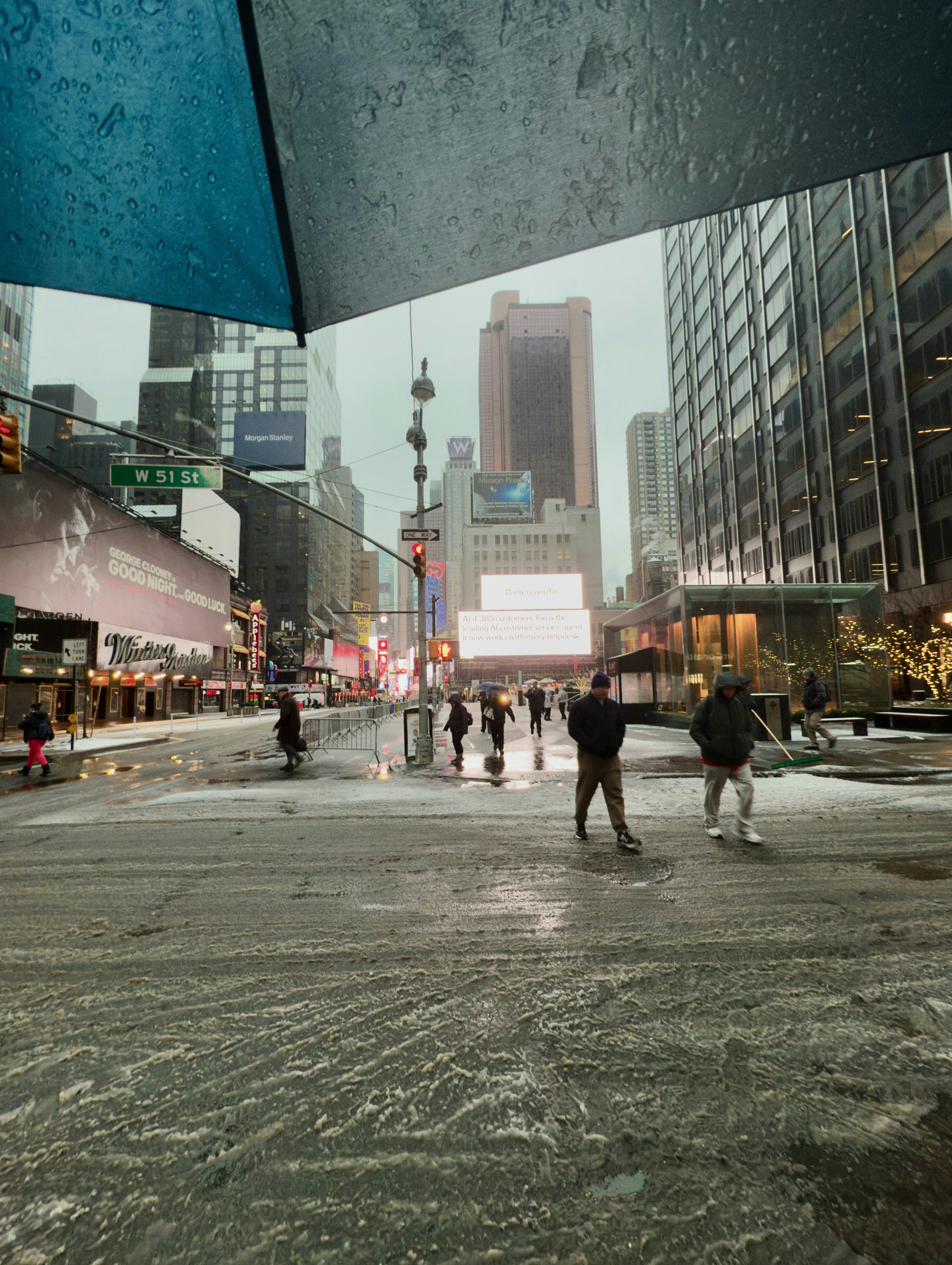 A group of people walking down a street next to tall buildings