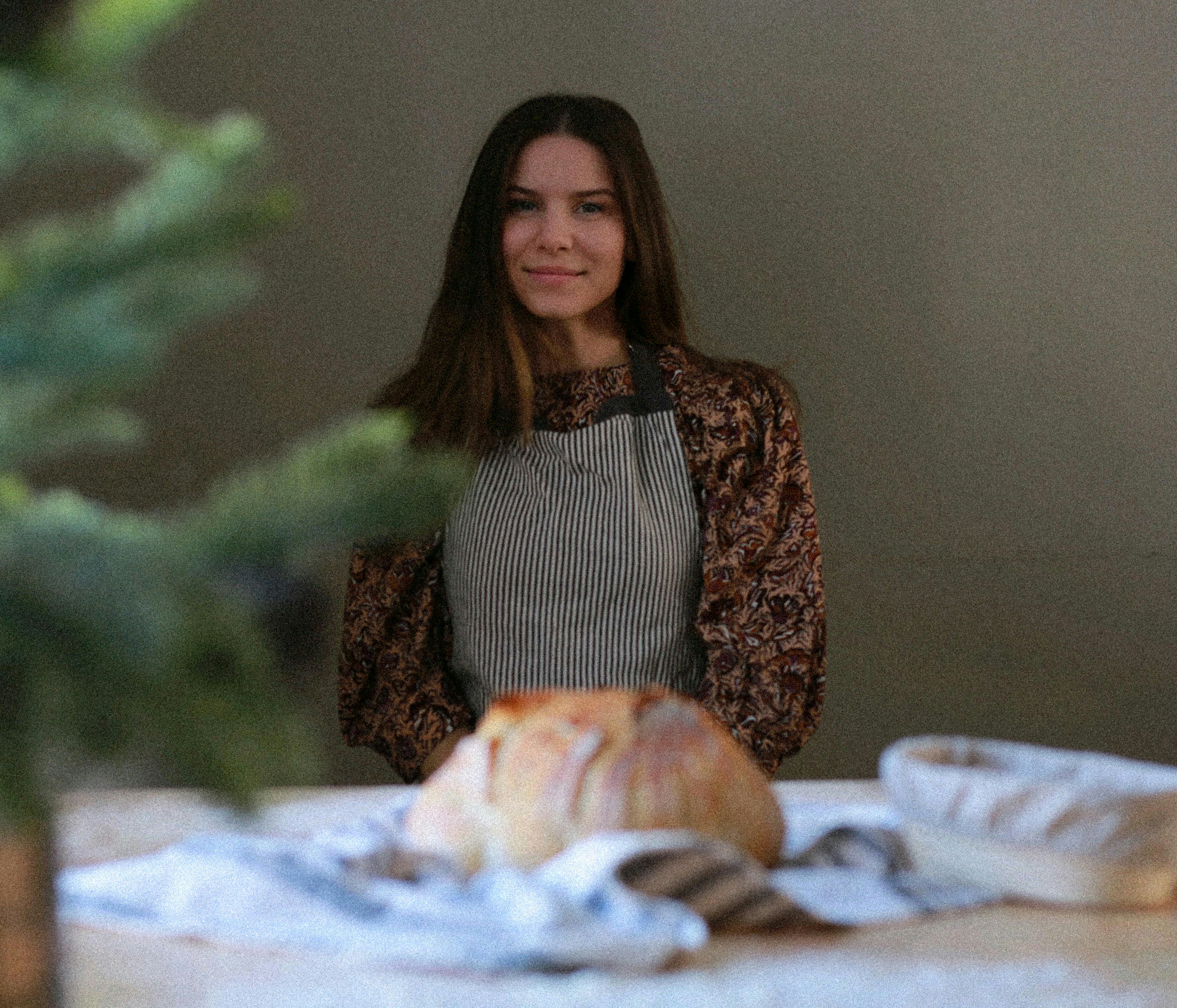 A woman standing in front of a table with a loaf of bread on it