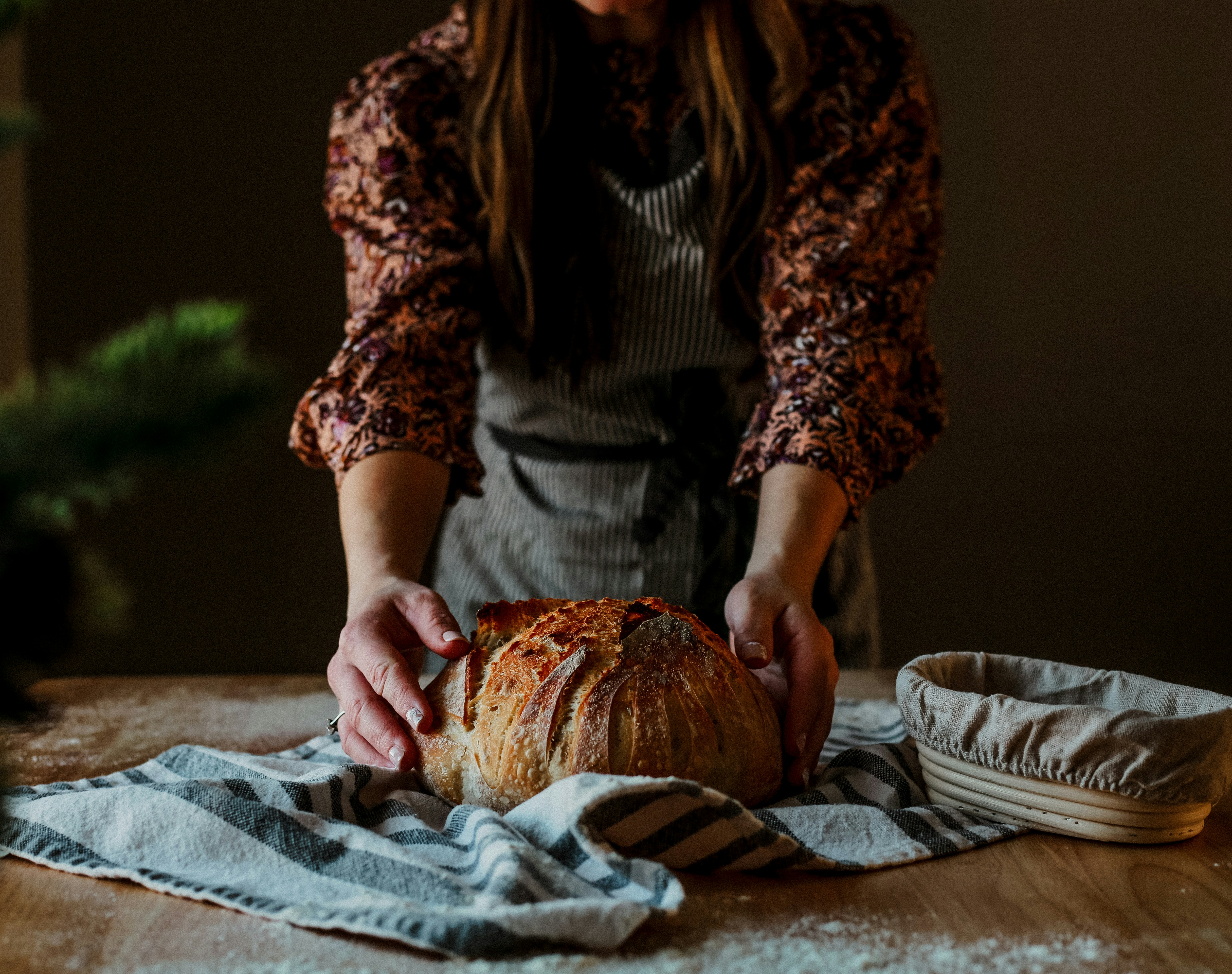 A woman preparing a loaf of bread on a table