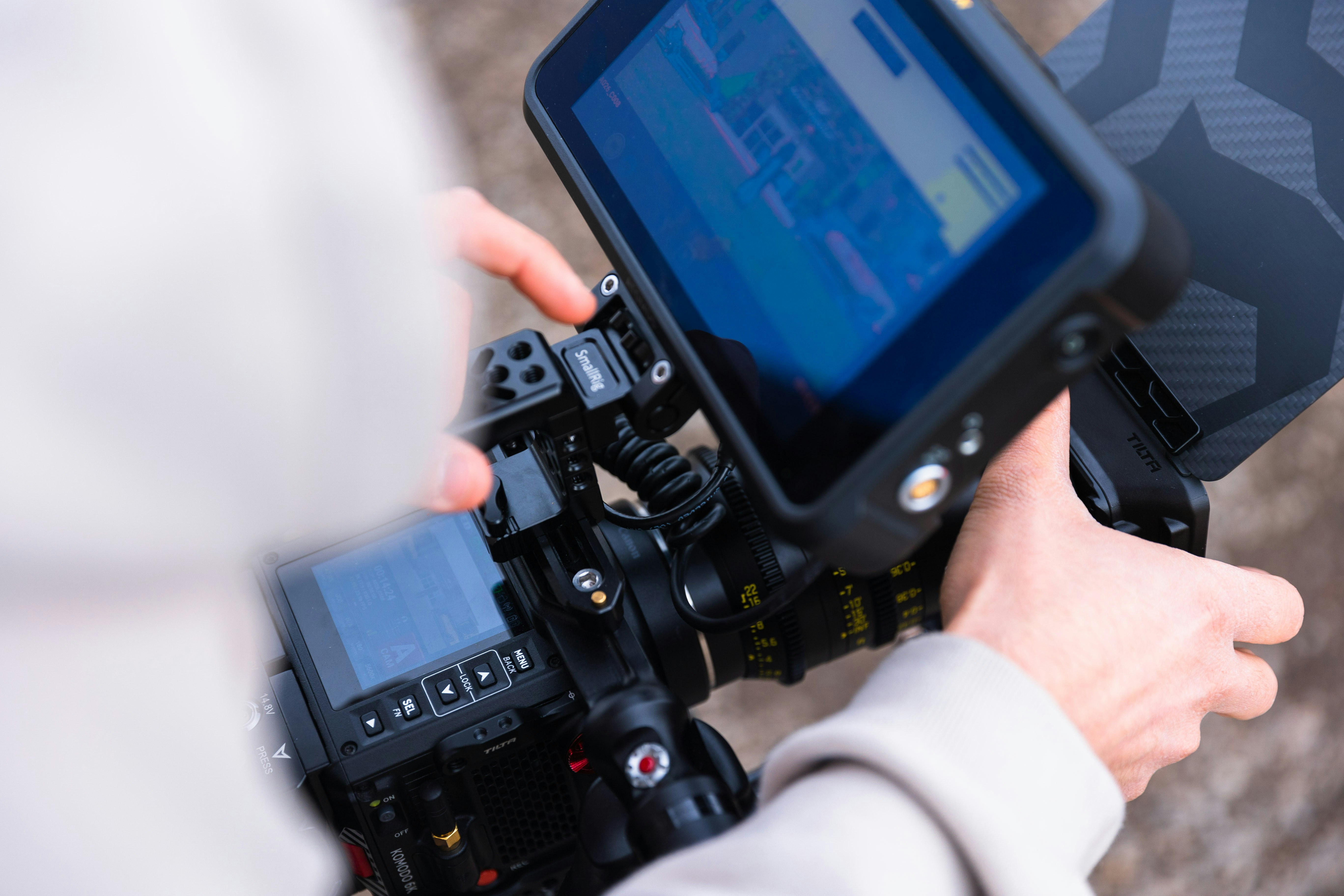 A person holding a camera with a monitor on top of it