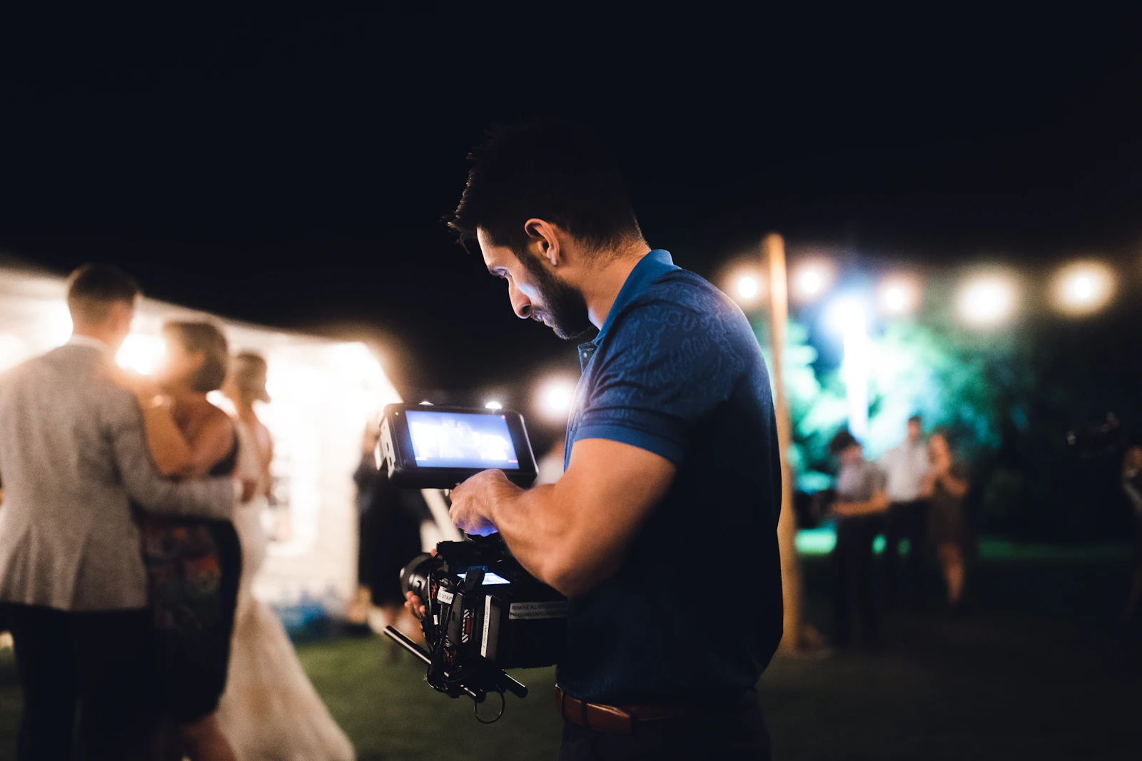 Un vidéaste de mariage filme un couple au tournage, caméra à l'épaule, pendant une cérémonie