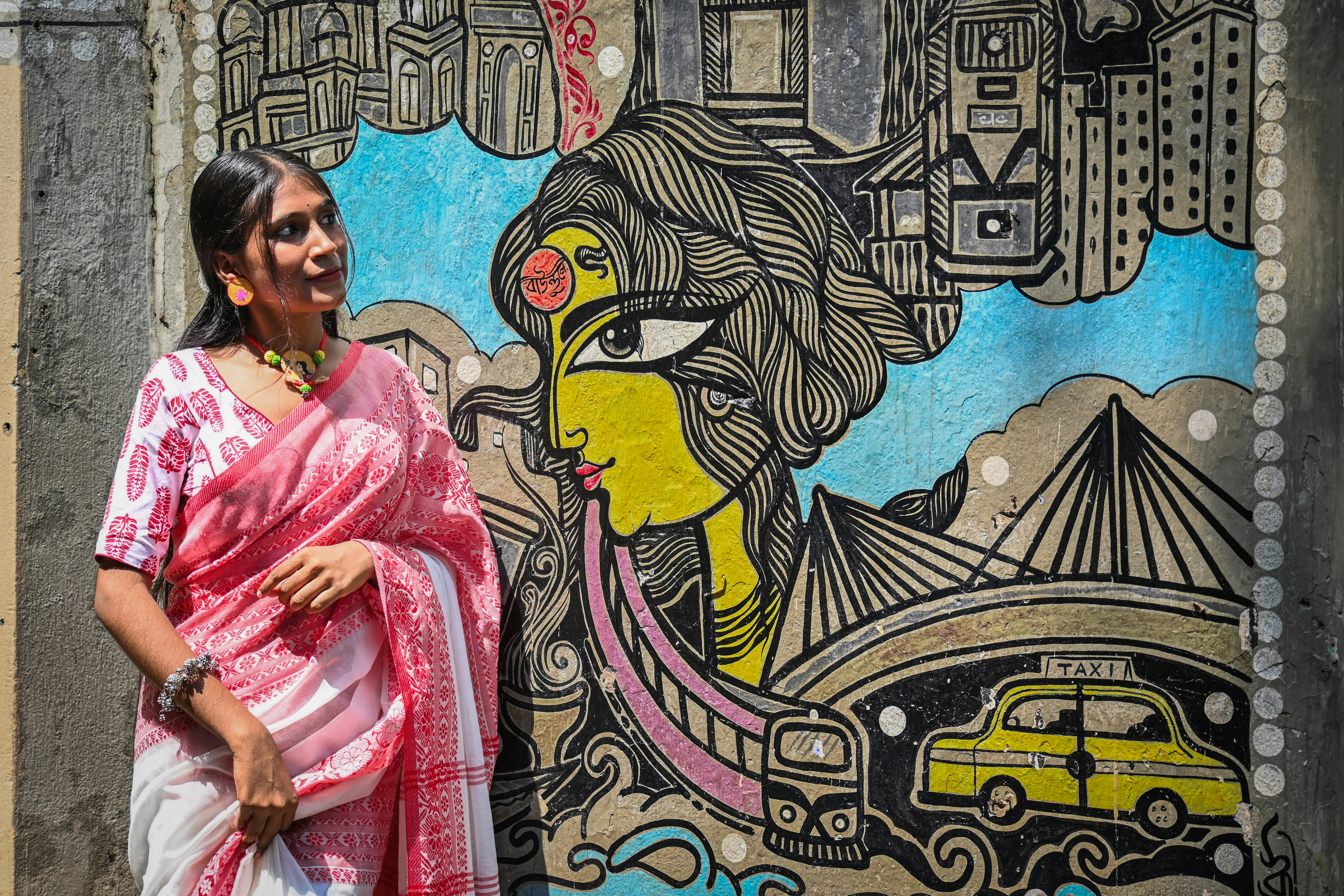 A woman standing in front of a wall with a painting on it