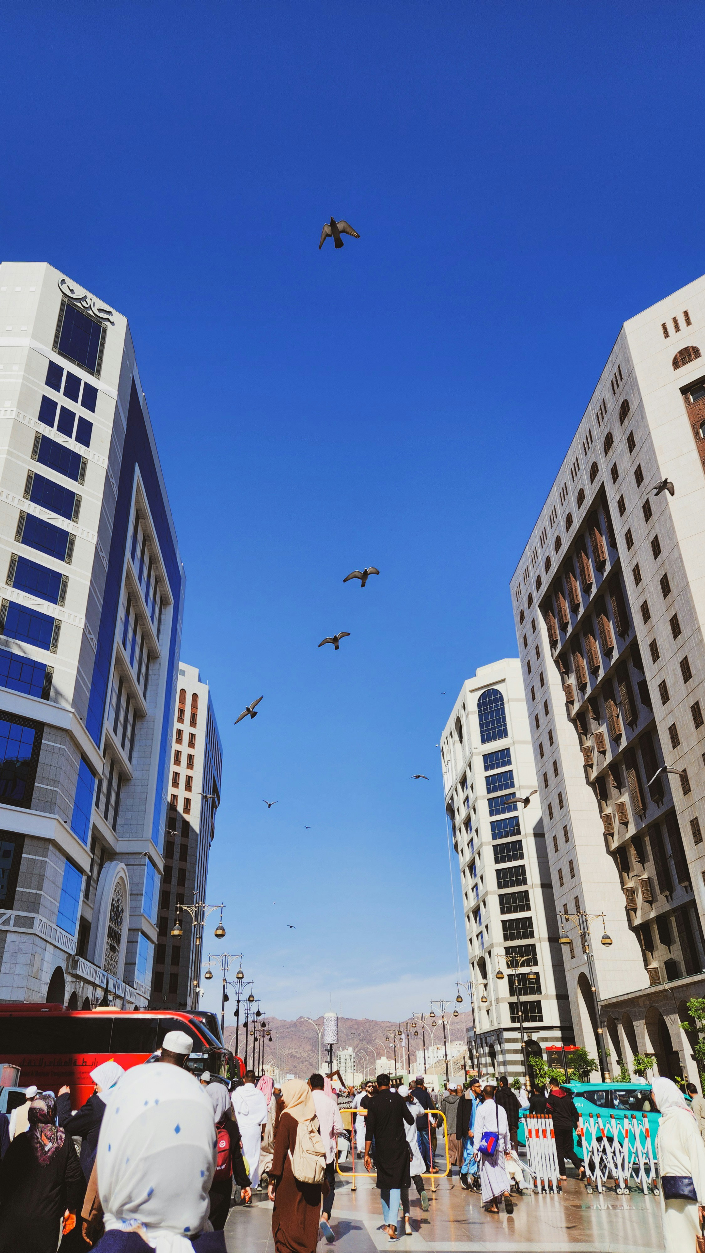 A group of people walking down a street next to tall buildings