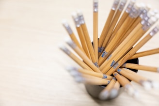 A cup filled with lots of pencils on top of a table