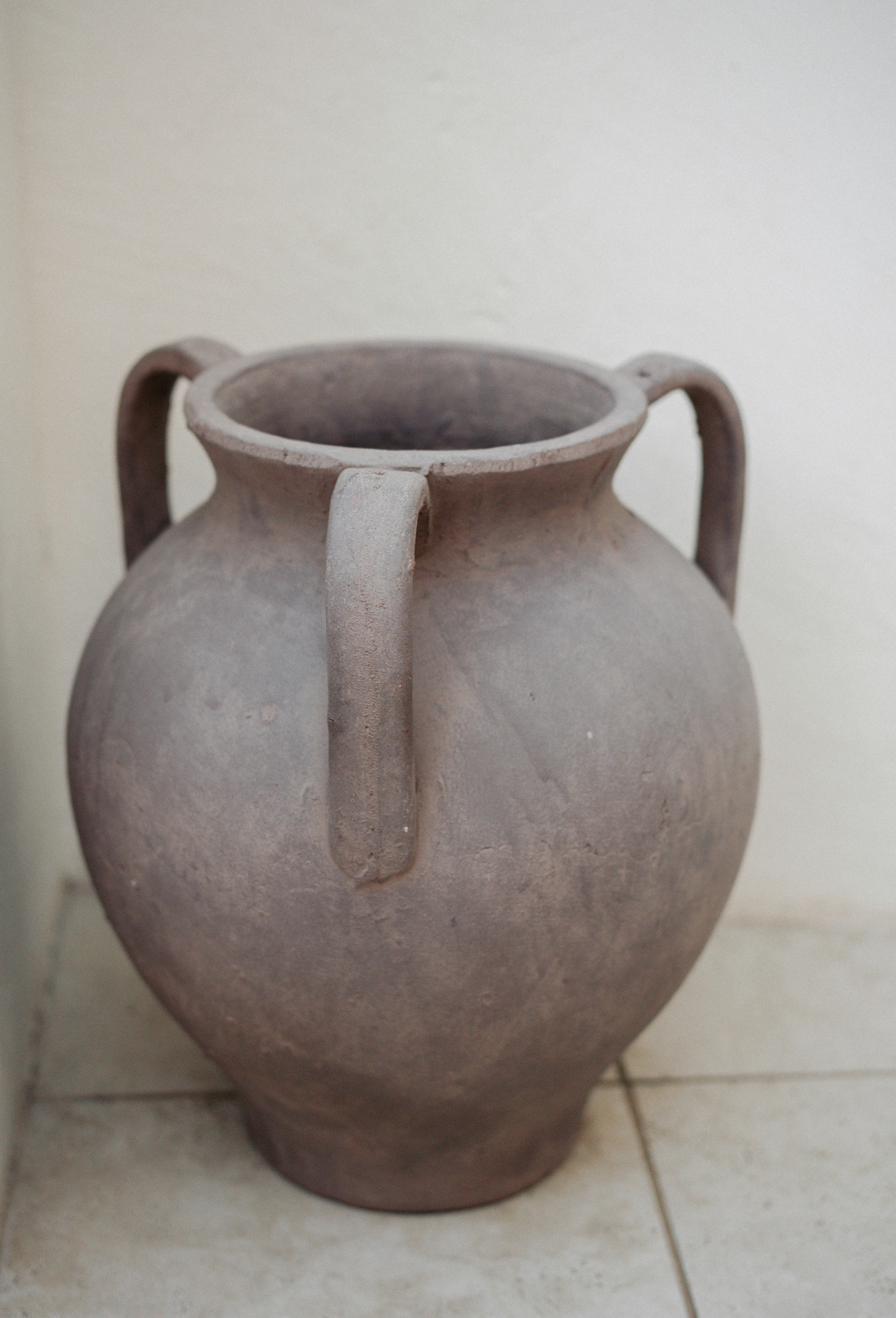 A large gray vase sitting on a tile floor