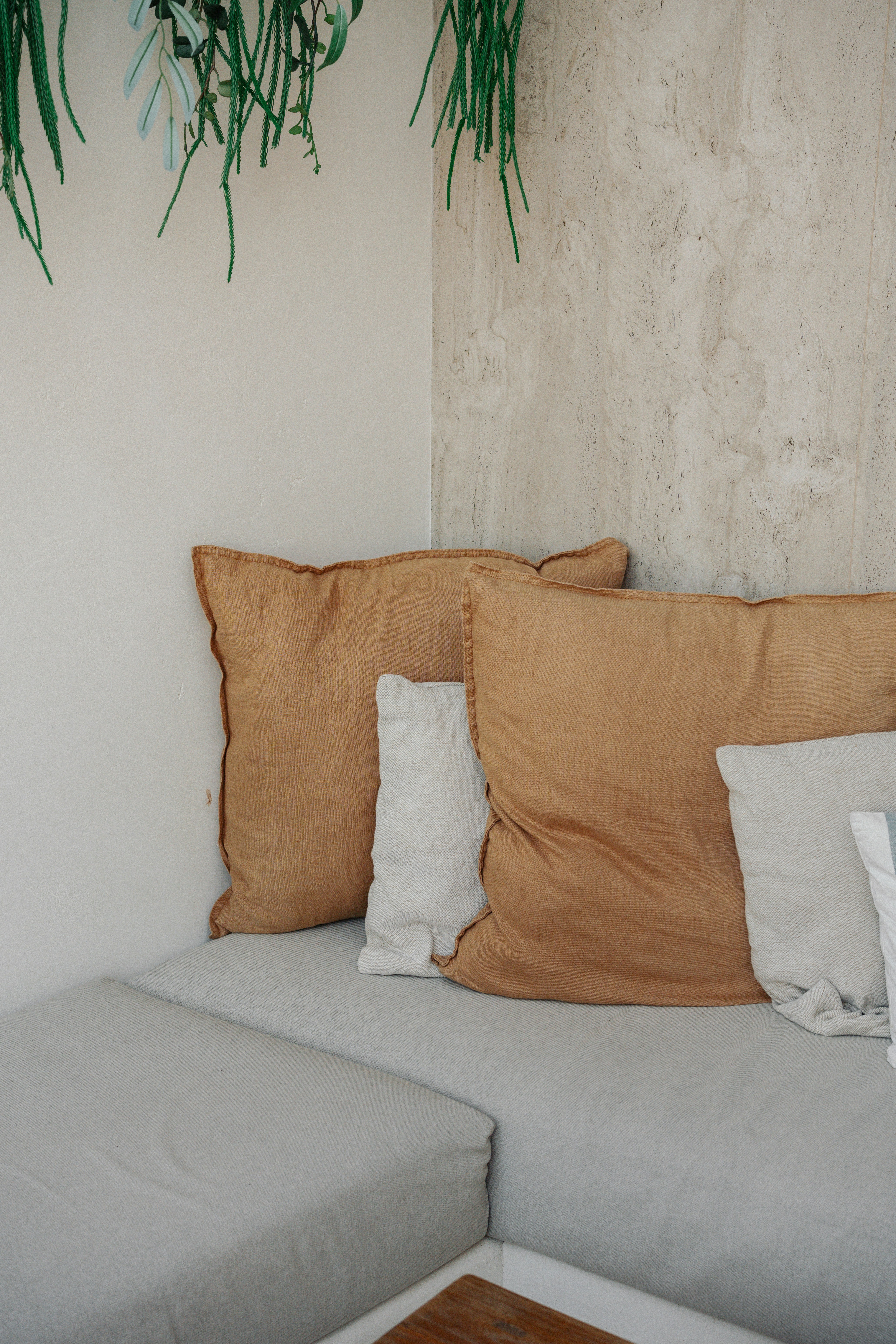 A couch with pillows and a plant hanging above it