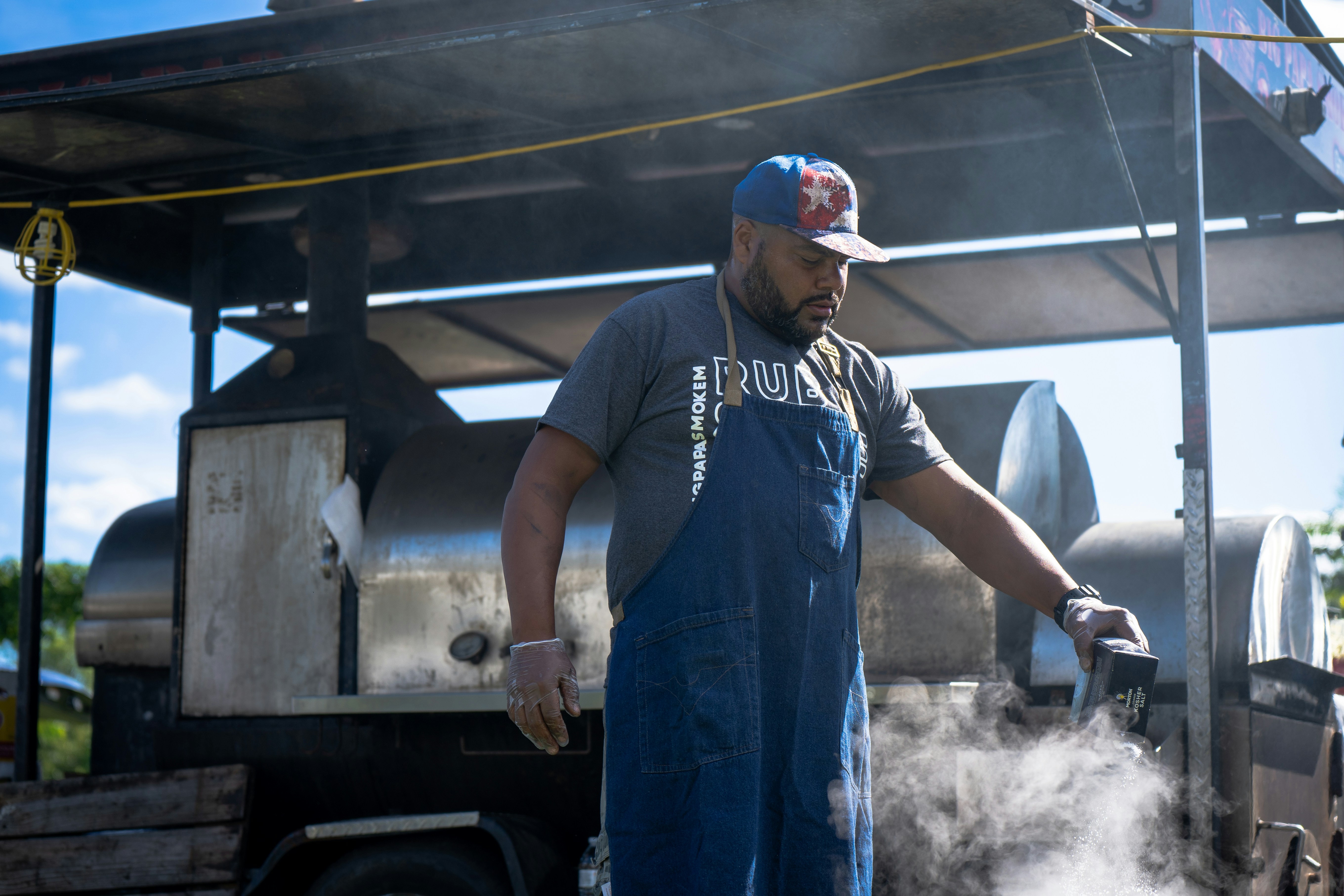 A man in overalls cooking on a grill