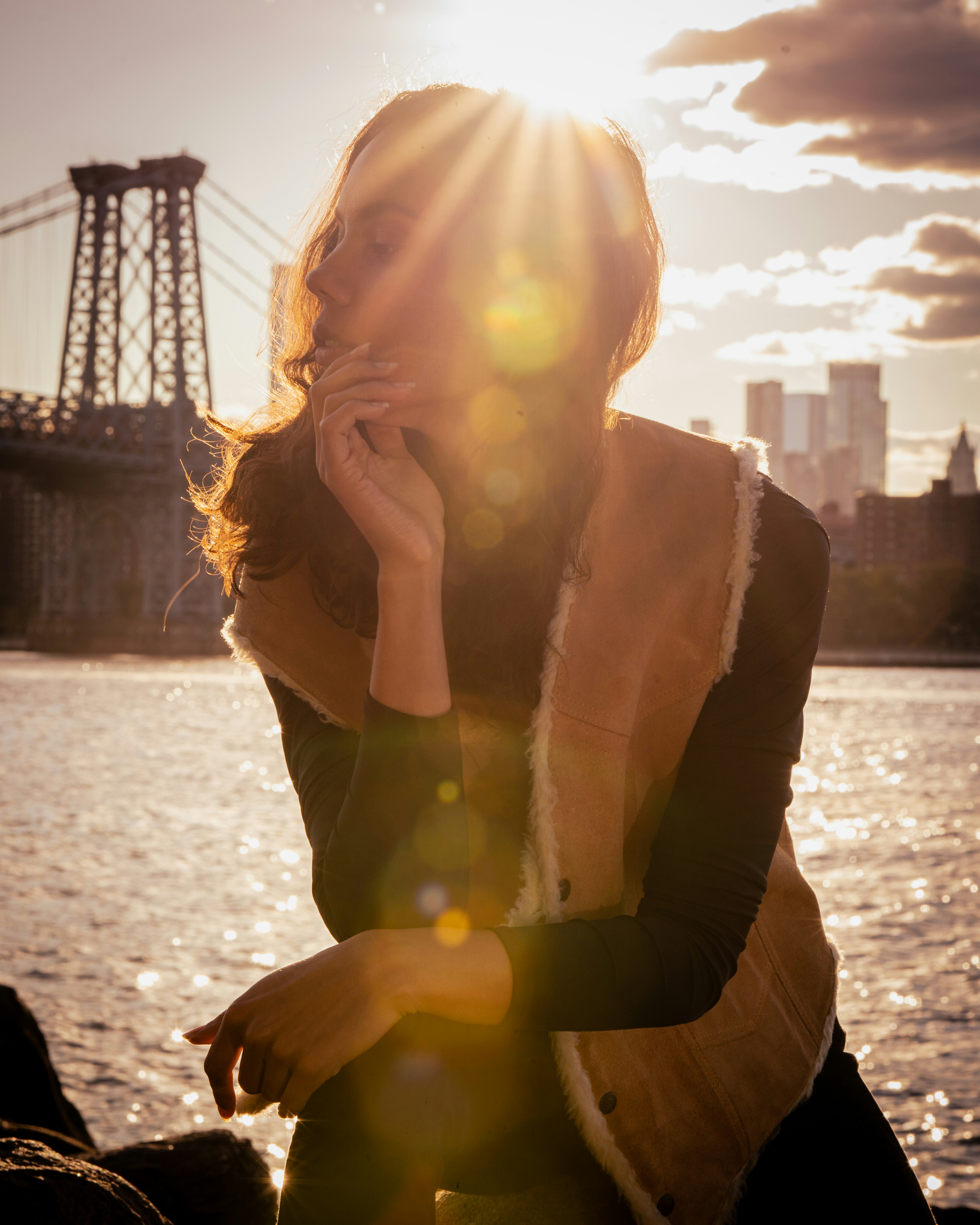 A woman sitting on a rock next to a body of water