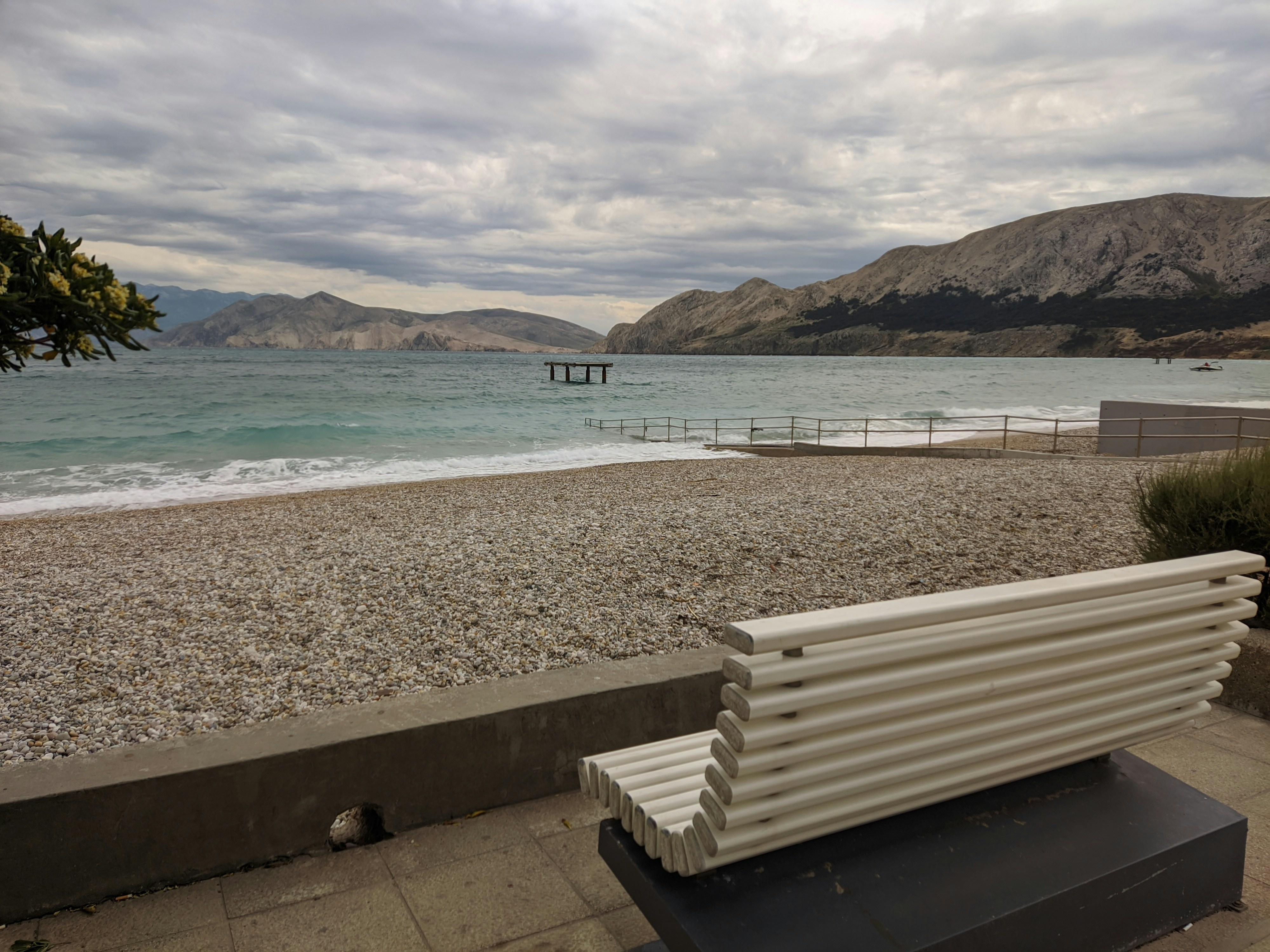 A bench sitting on the side of a beach photo – Free Wallpaper Image on ...