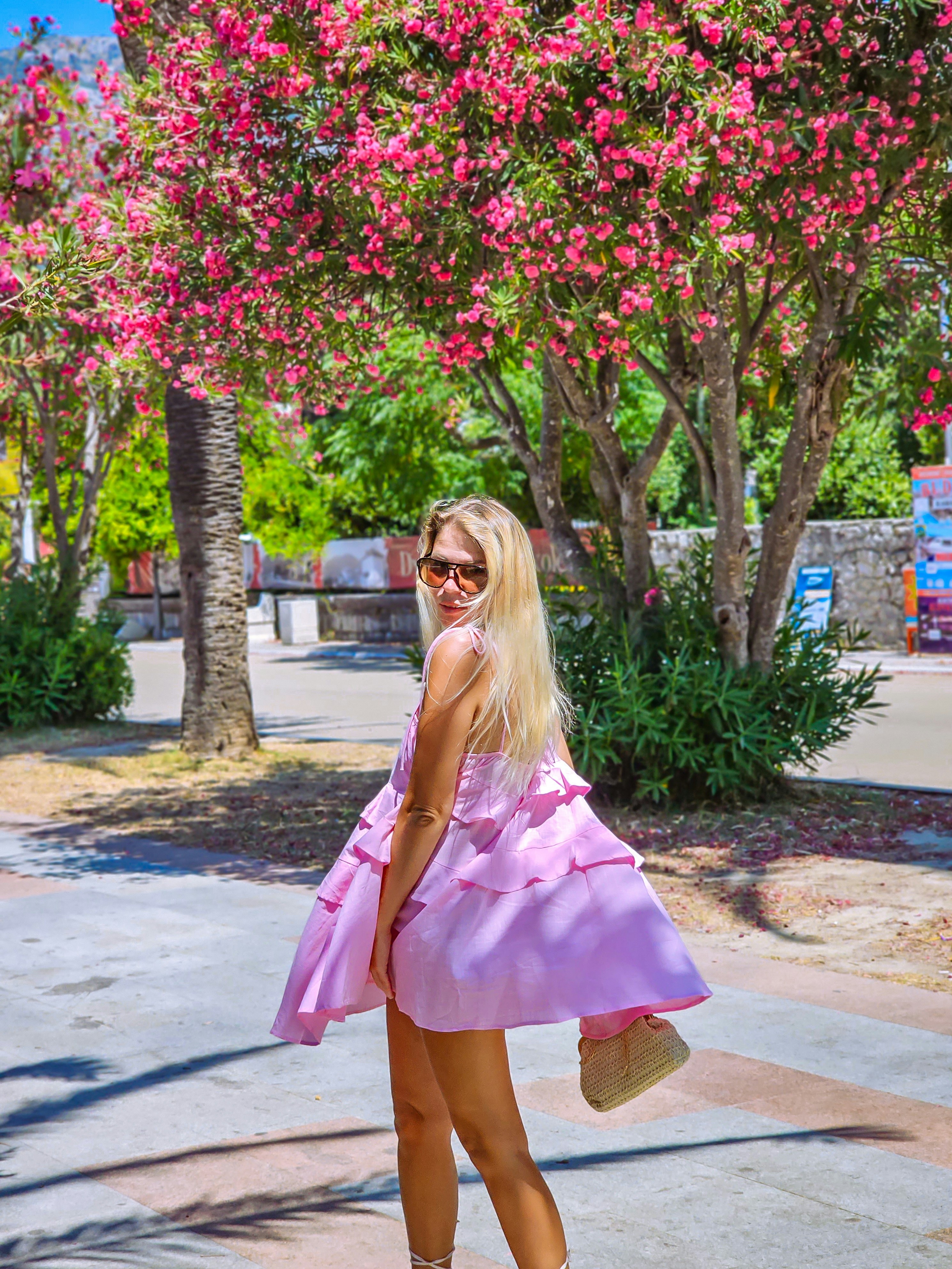 A woman in a pink dress standing on a sidewalk