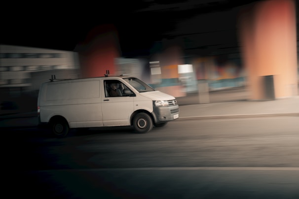 A white van driving down a street at night