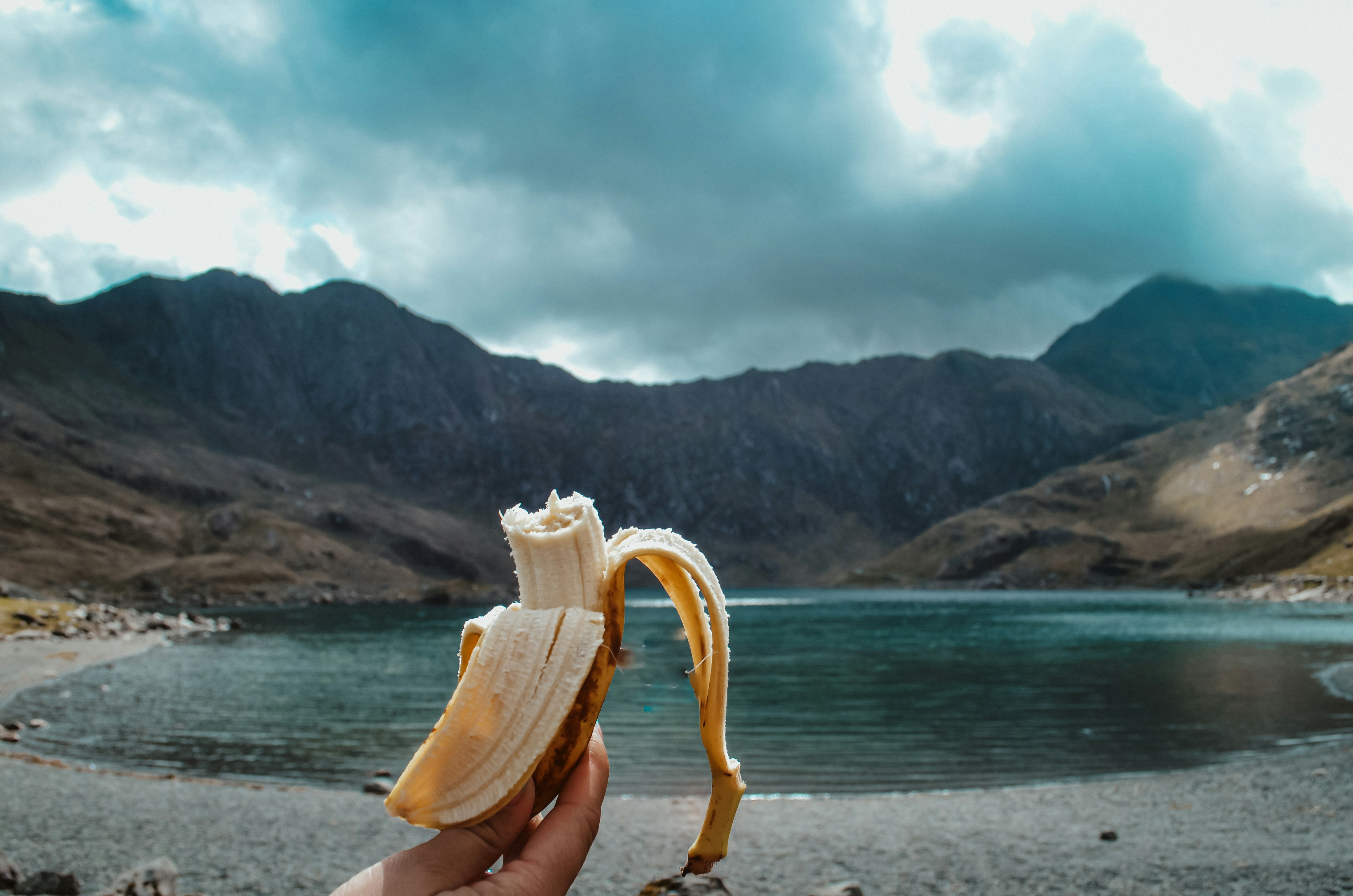 A person holding a banana in front of a body of water