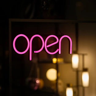 A neon sign that says open in a dark room