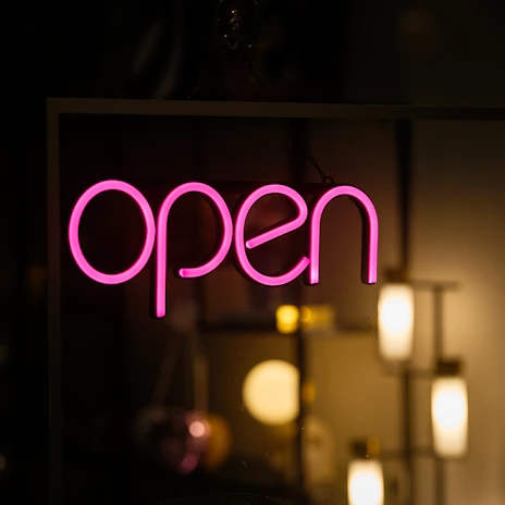 A neon sign that says open in a dark room