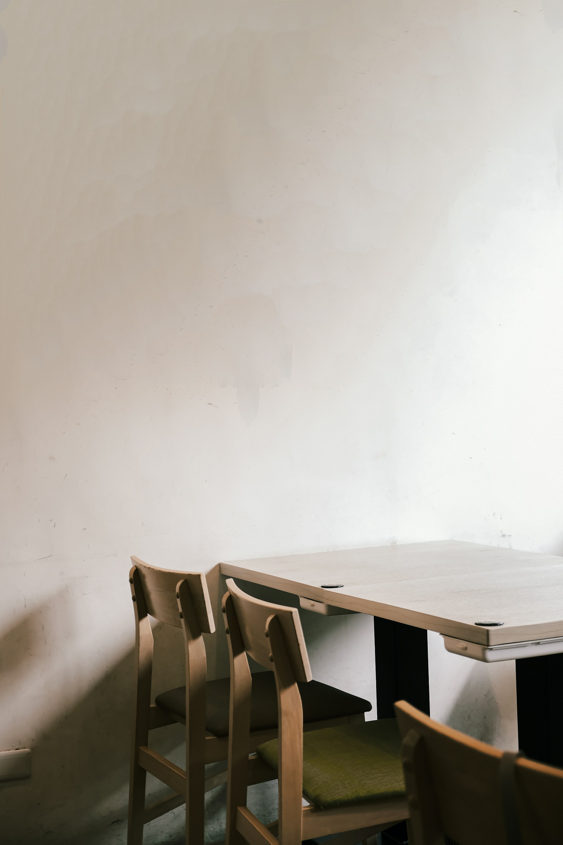 A table and chairs in a room with a white wall