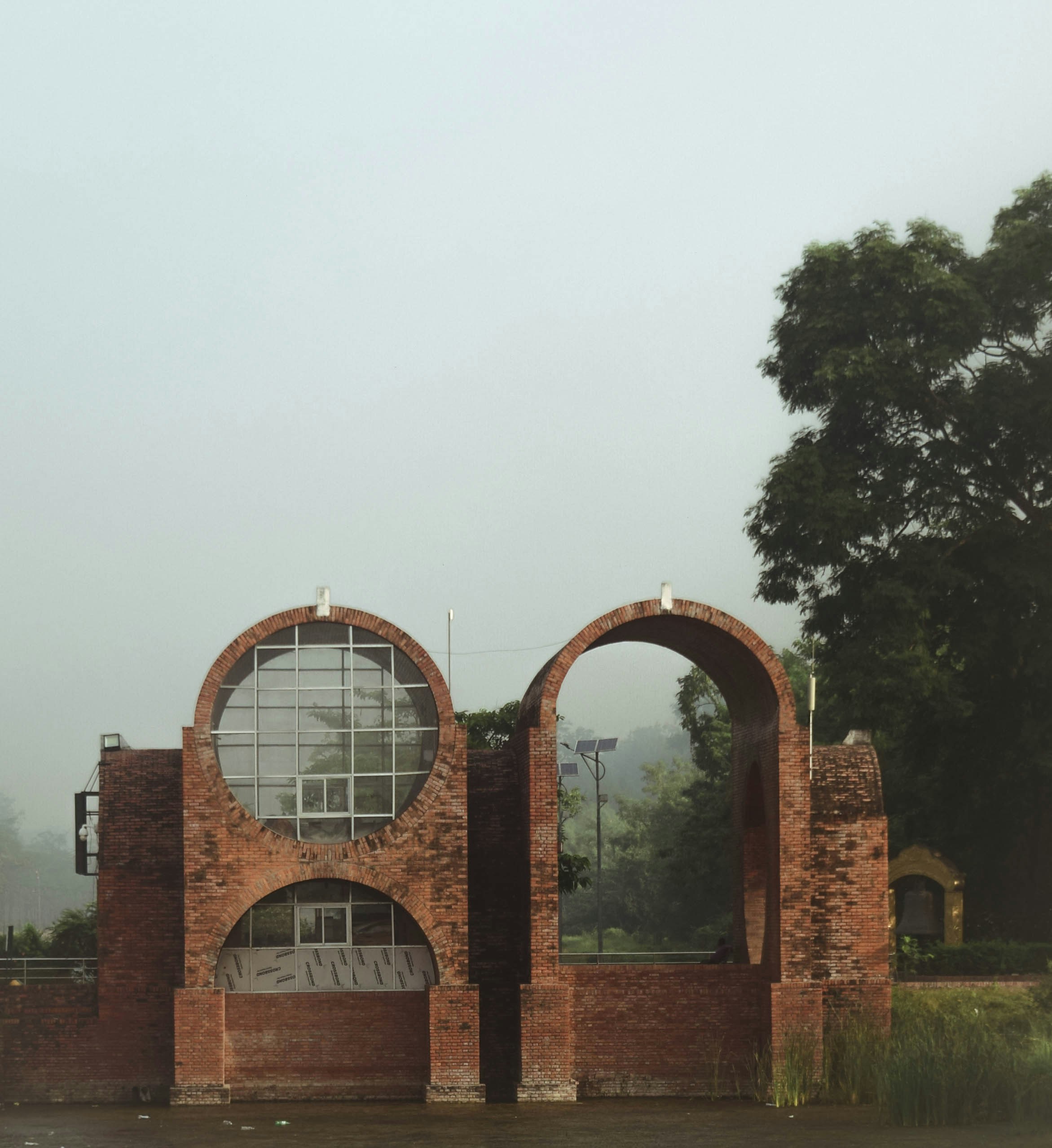 An old brick building with arched windows in the middle of a field