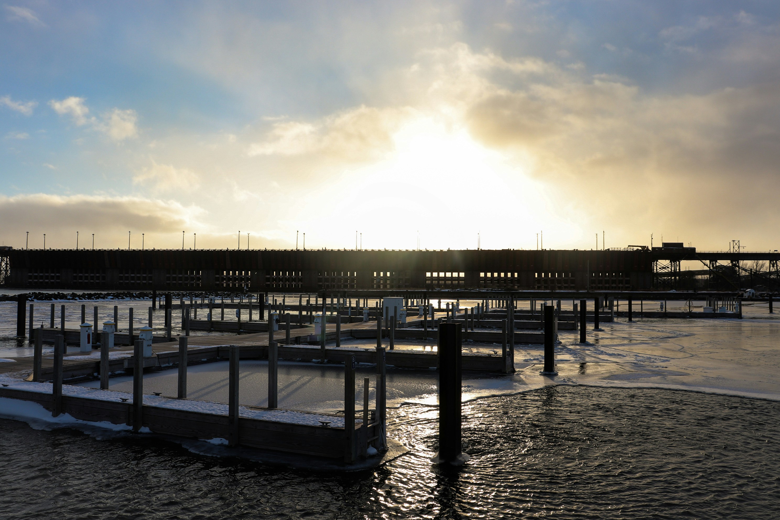 The sun is setting over a pier on the water