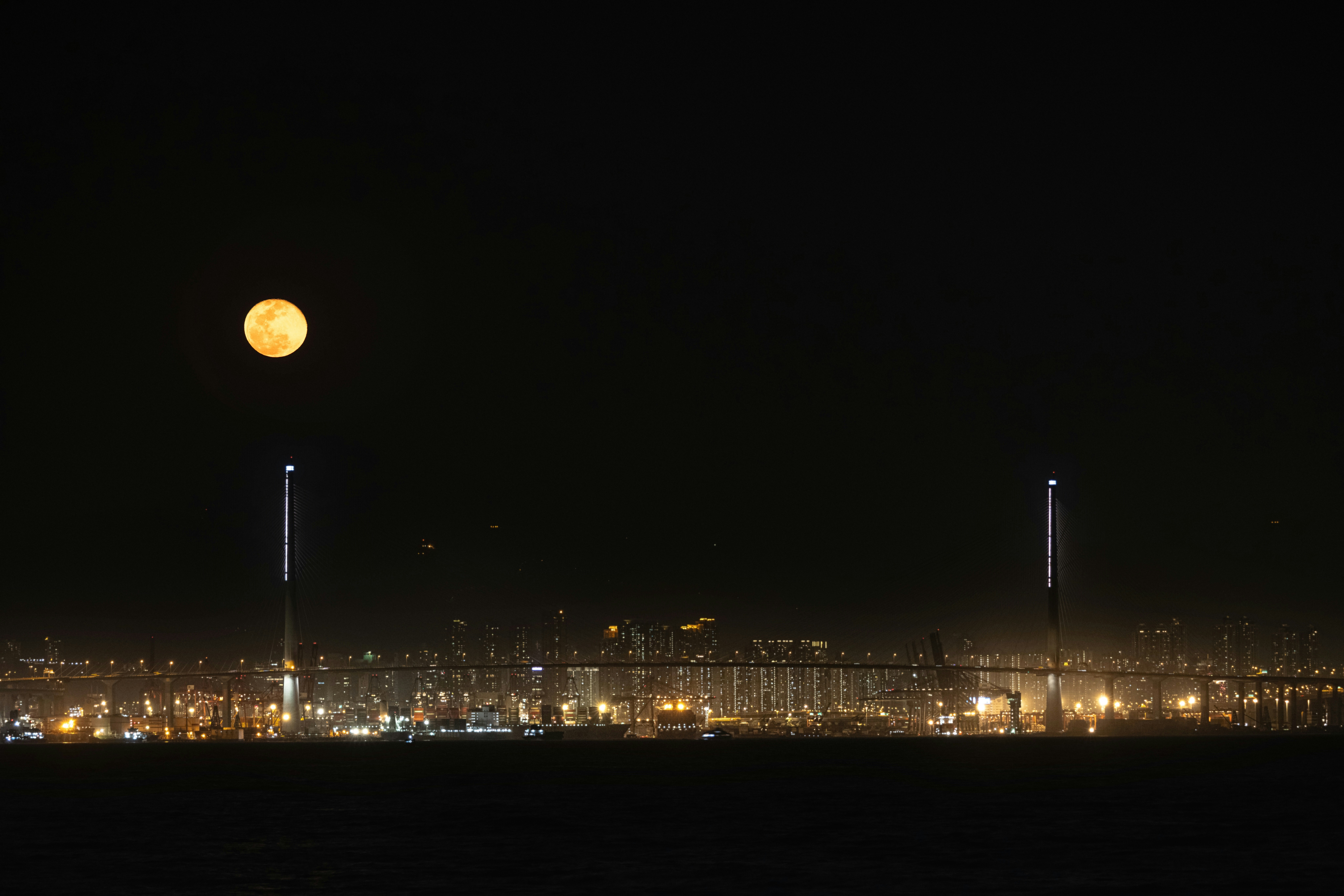 A full moon rising over a city at night