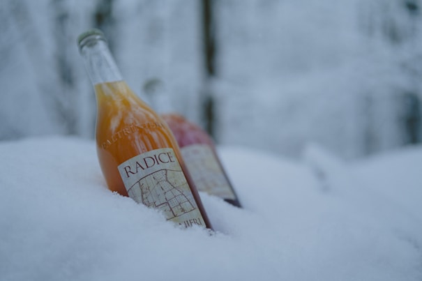 Two bottles of orange juice sitting in the snow