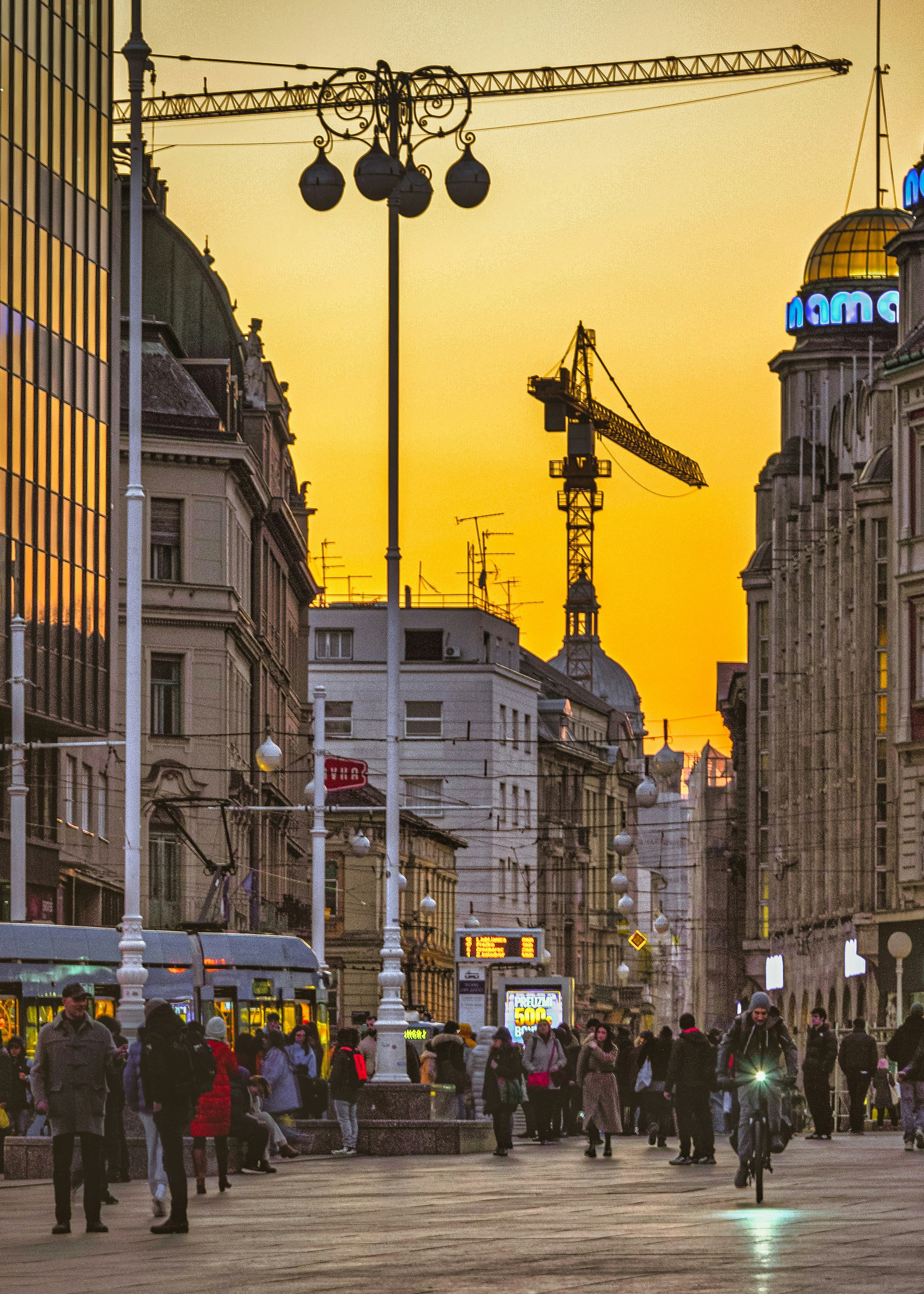 A group of people walking down a street next to tall buildings