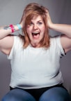 A woman sitting on a chair with her hands on her head