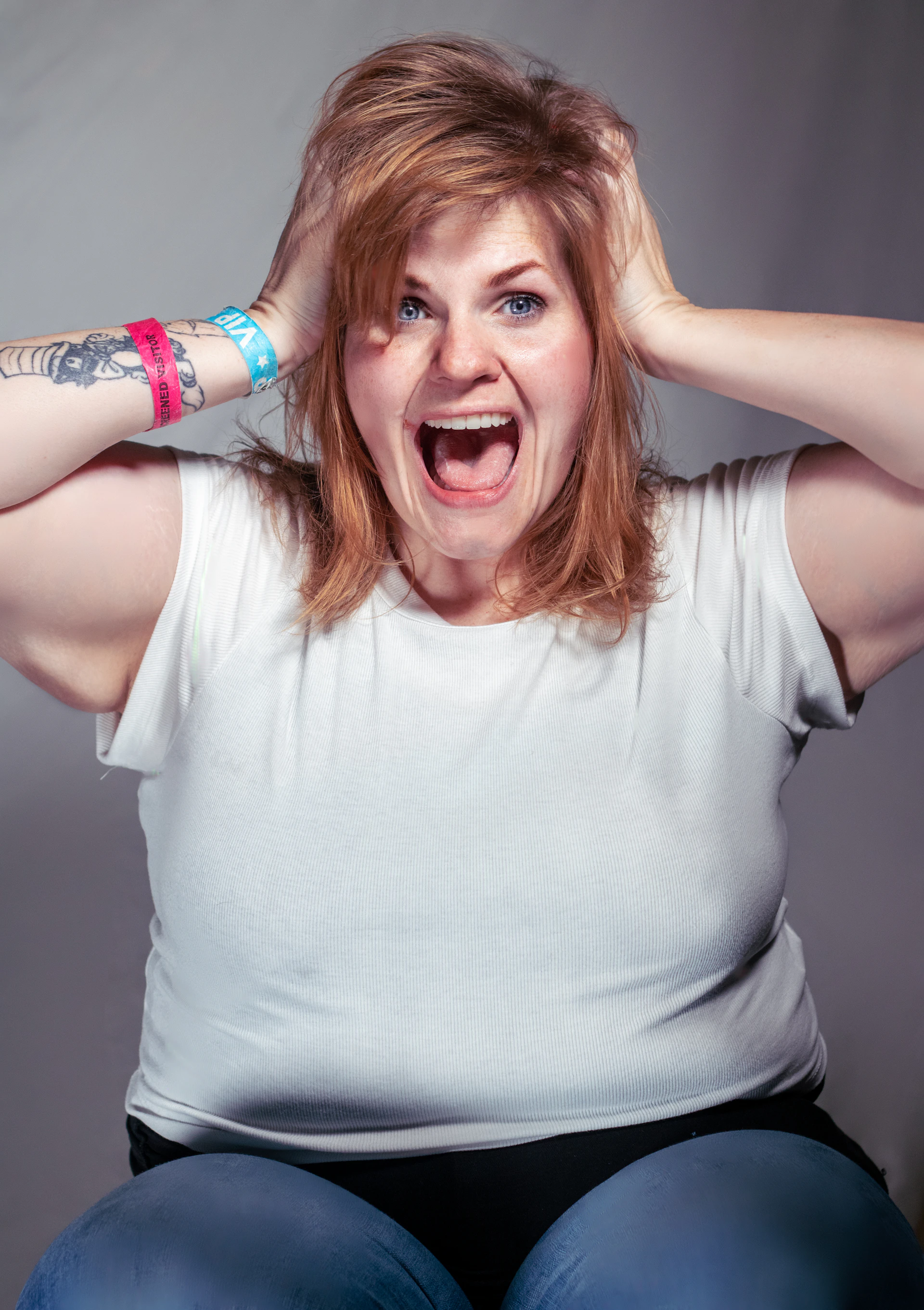 A woman sitting on a chair with her hands on her head
