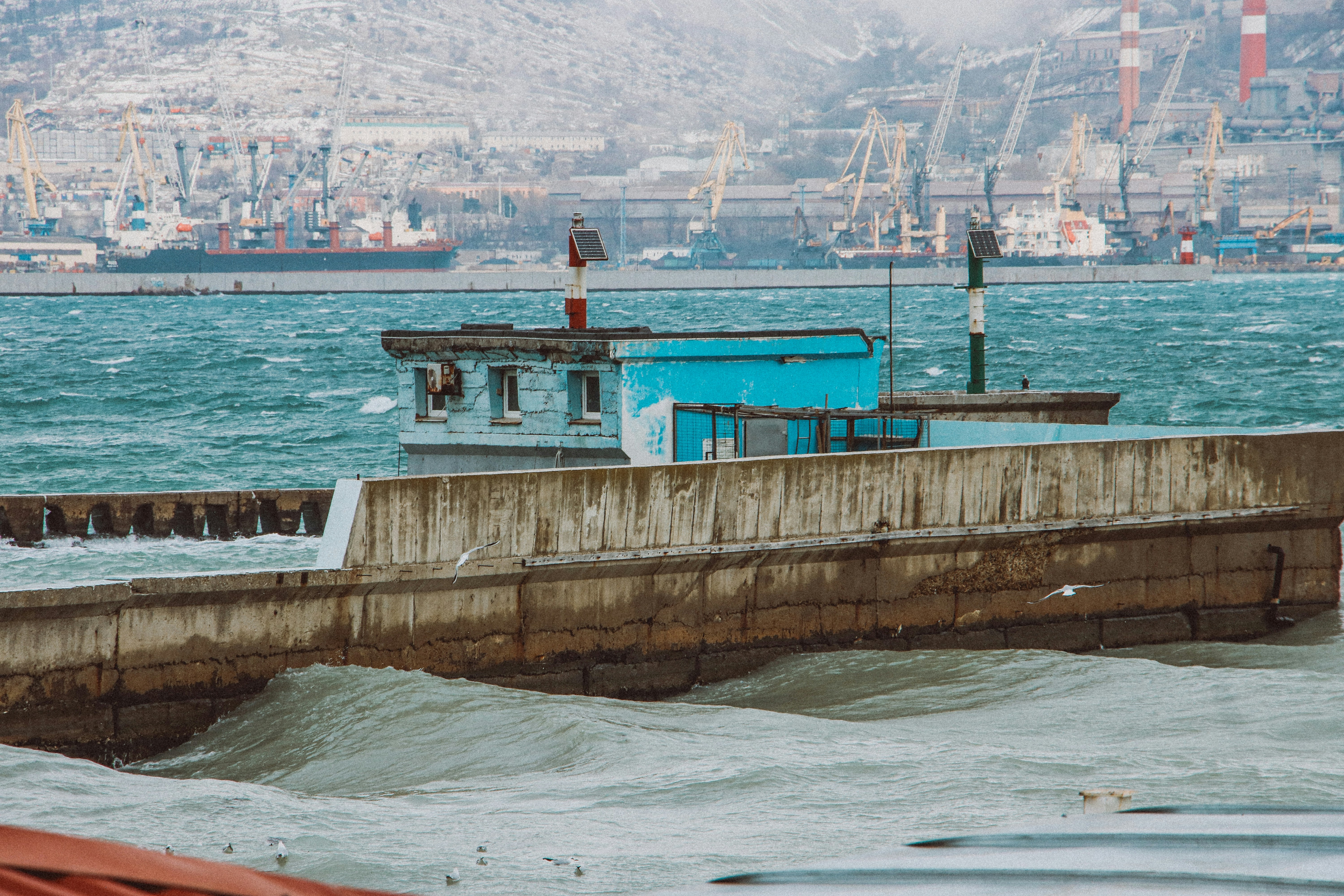 A blue boat in the water next to a pier