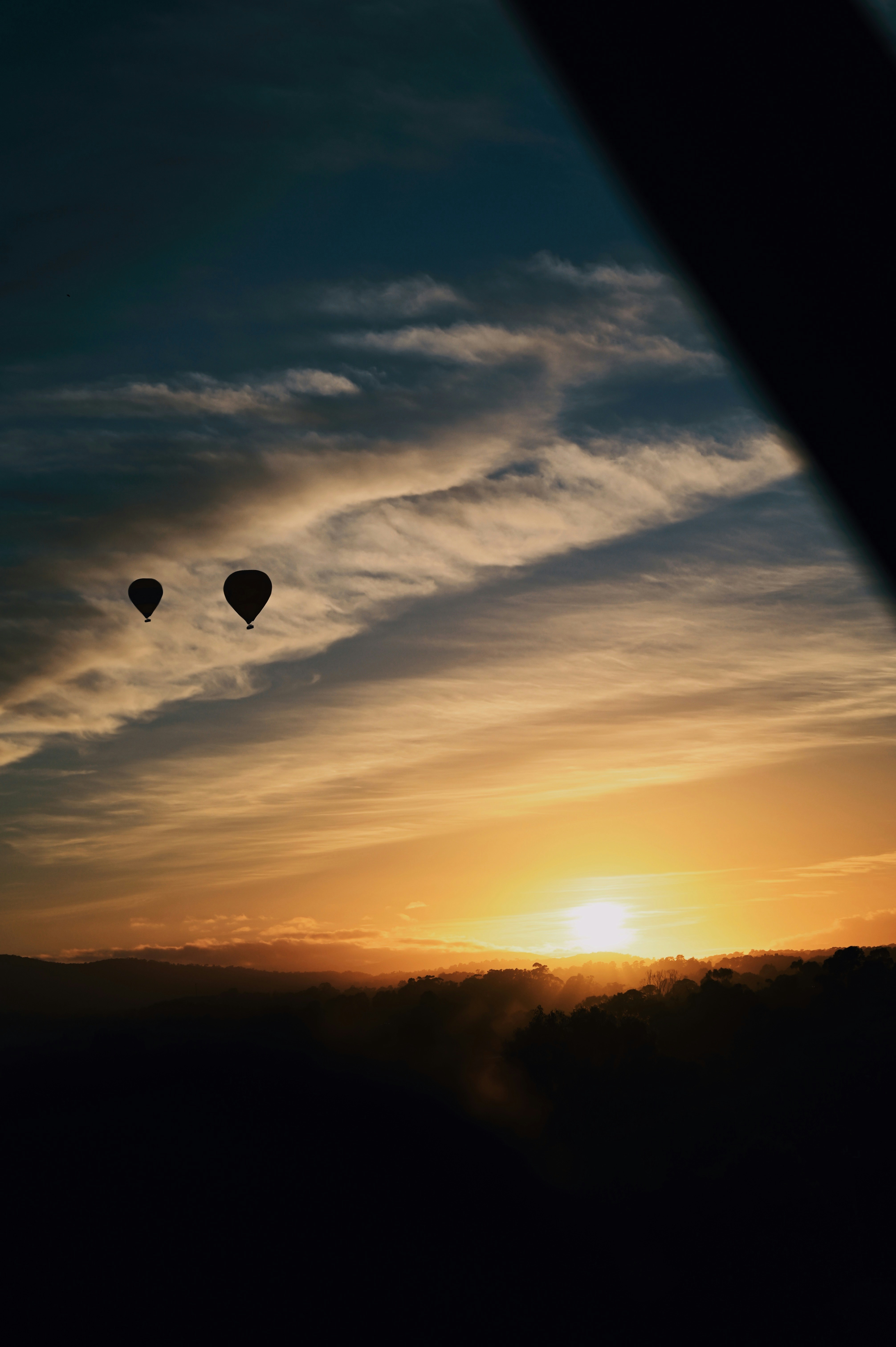 Three hot air balloons flying in the sky at sunset