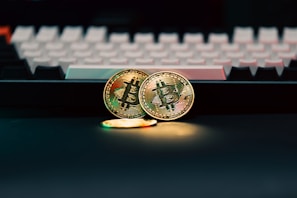 Two bitcoins sitting next to a computer keyboard