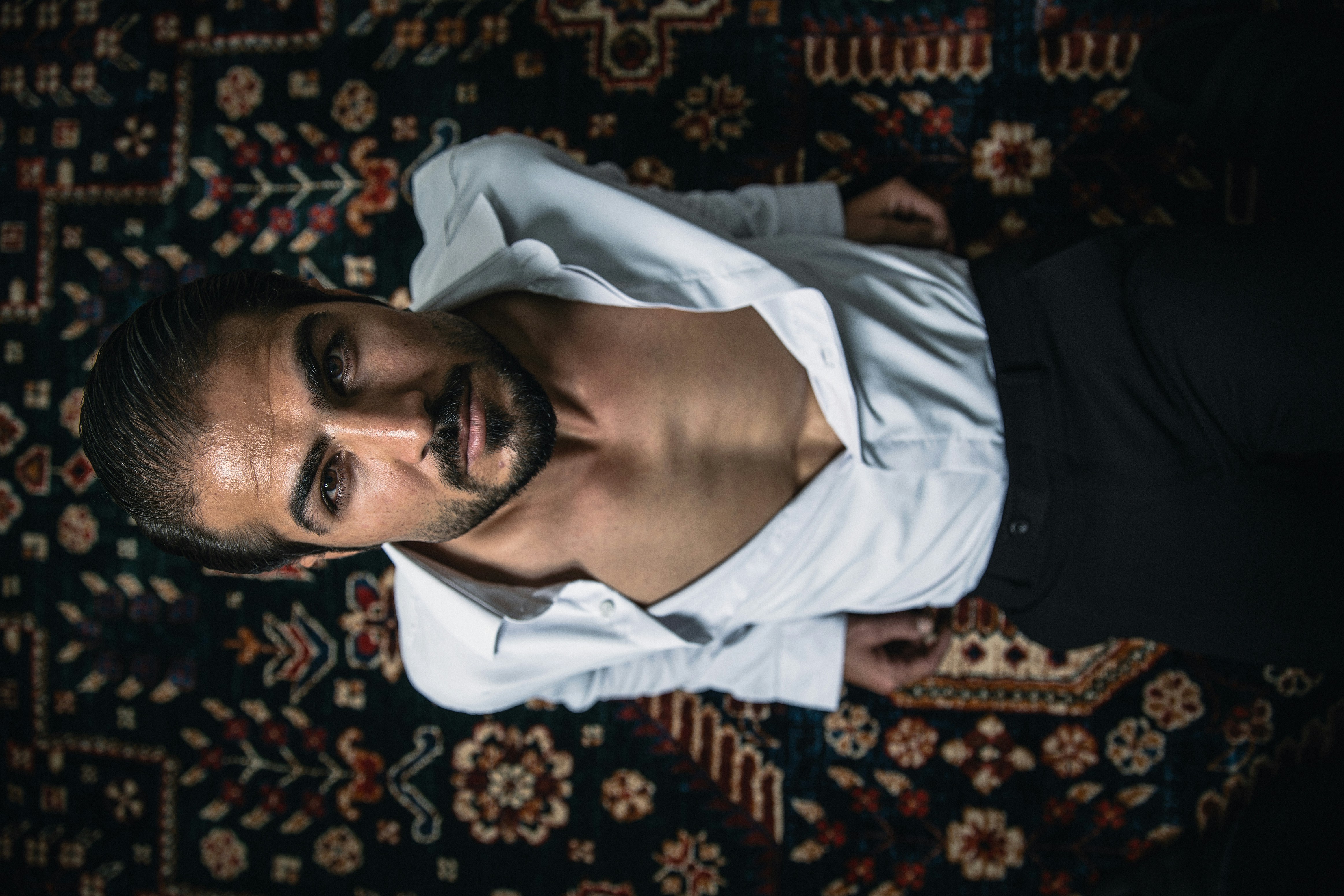 A man in a white shirt is laying on a rug photo – Free Portrait Image ...