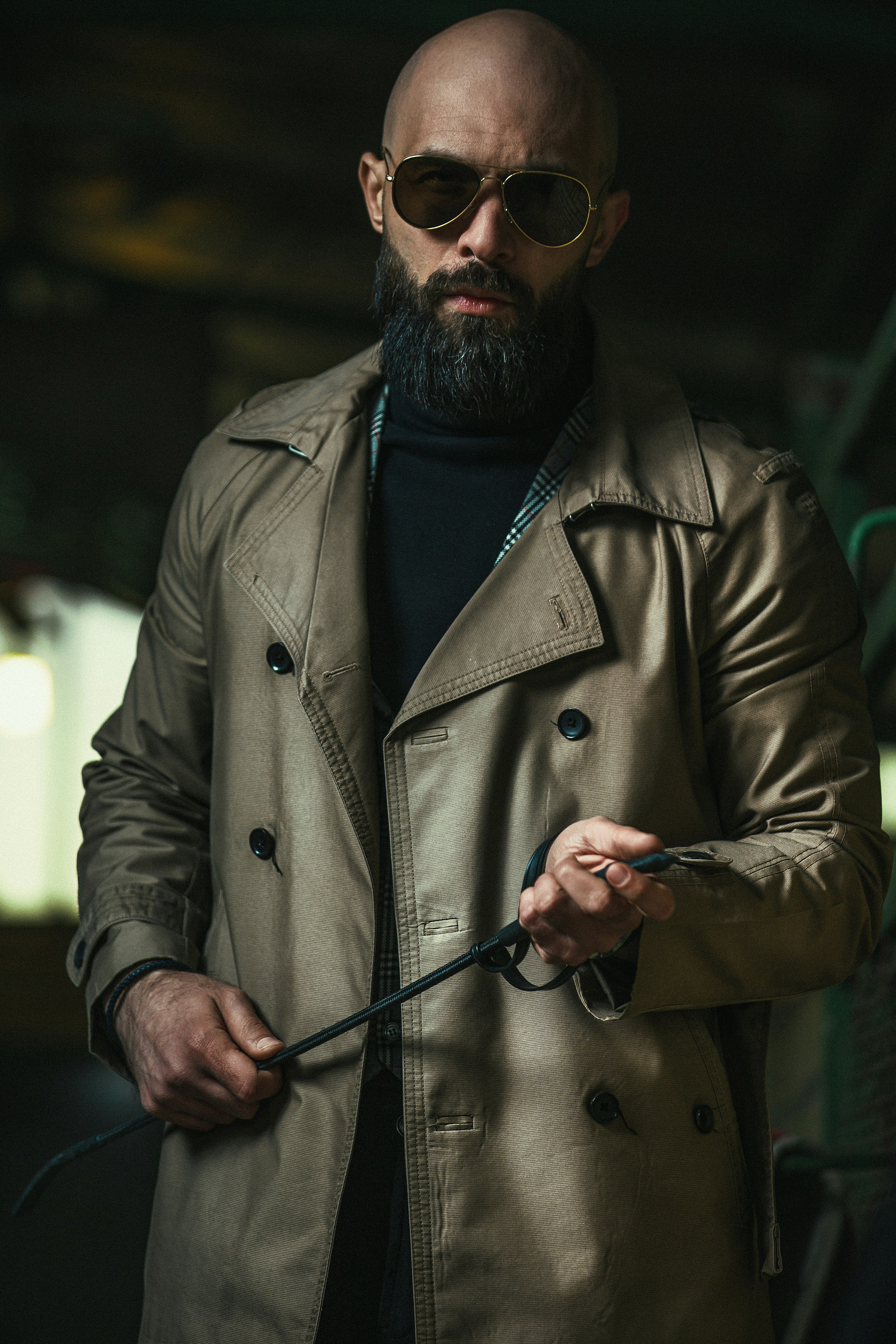A man in a trench coat holding a whip