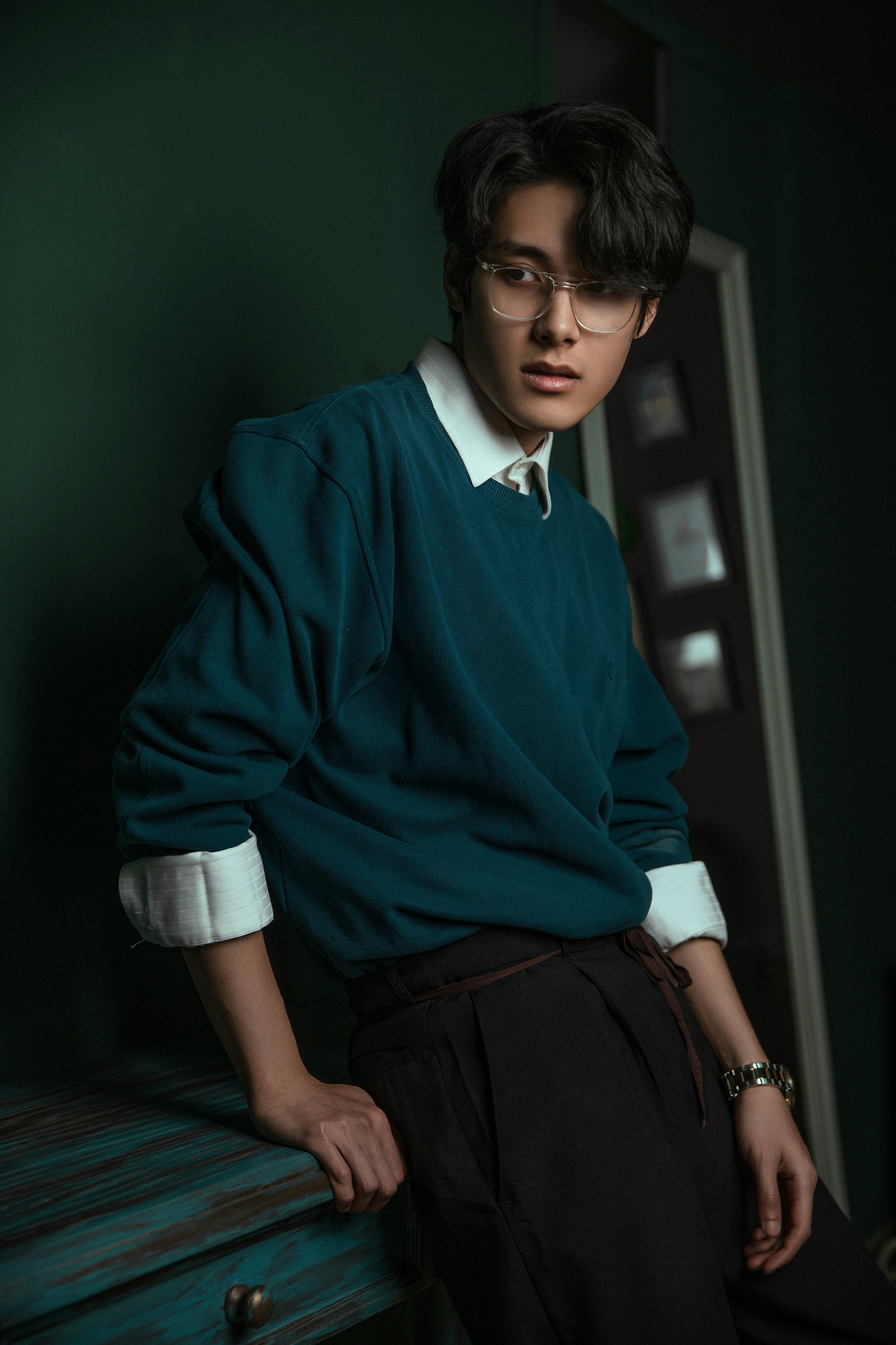 A man in a green sweater leaning on a bench