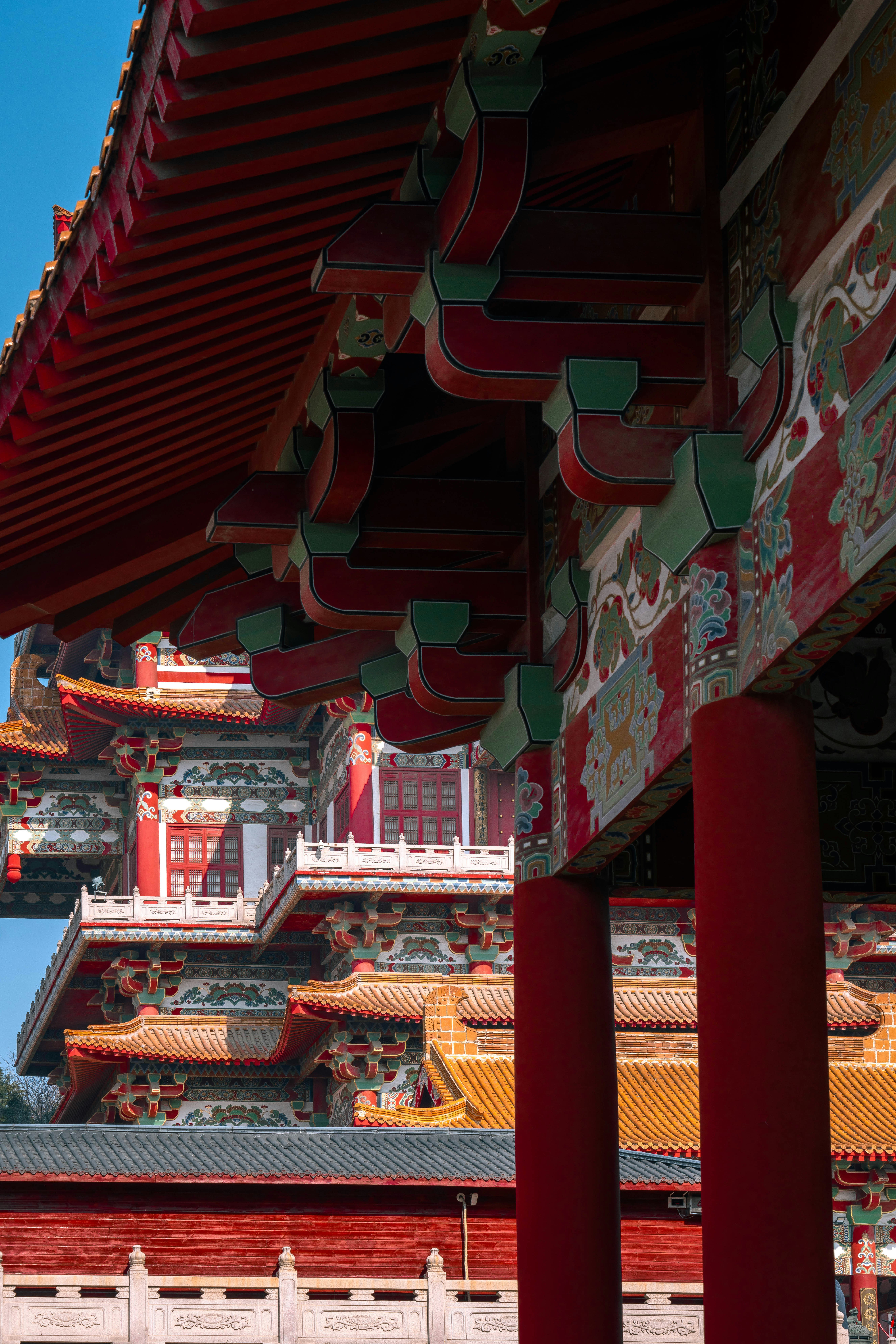 A tall building with red pillars and a clock tower in the background